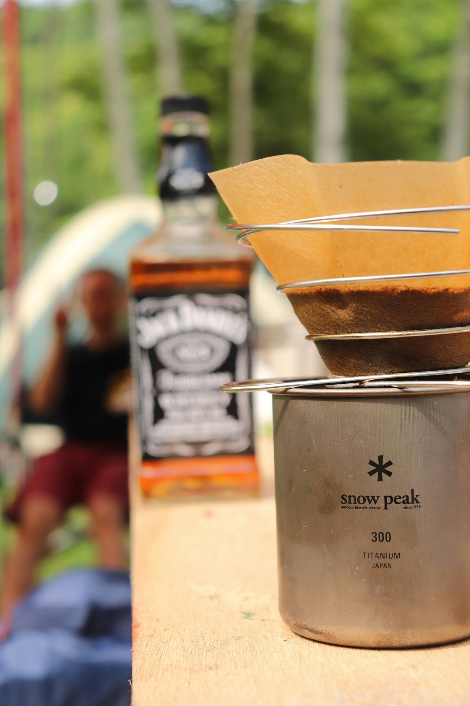 Cảnh pha cà phê tại một nơi cắm trại với chai rượu whisky ở phía sau