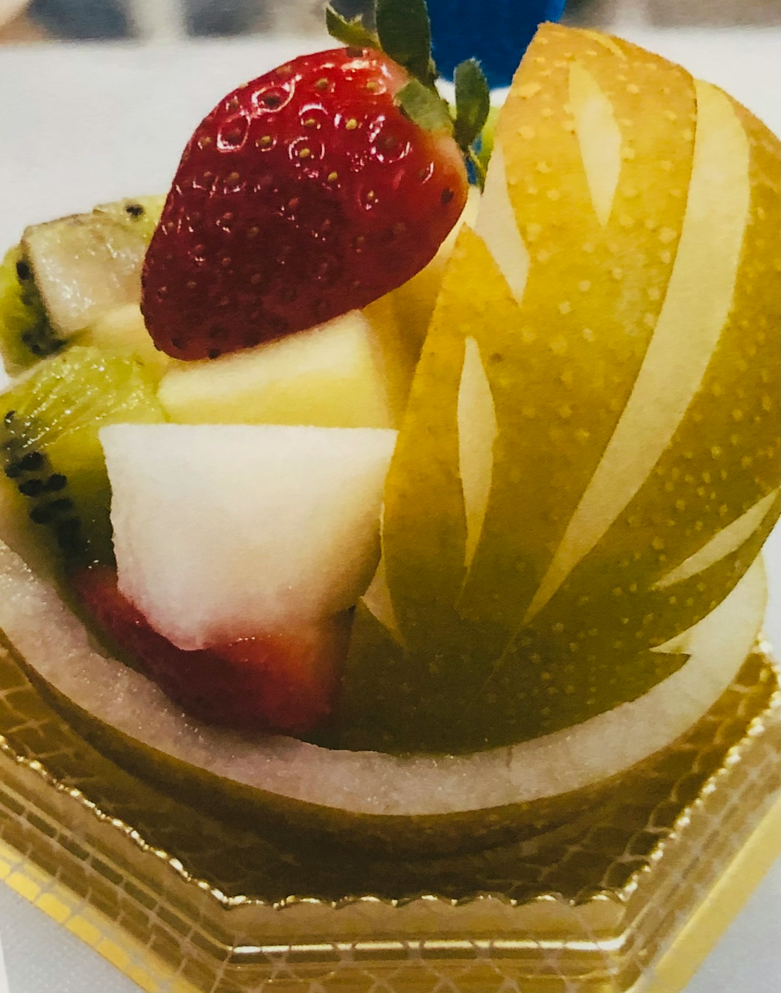 A beautiful fruit tart dessert featuring green apple, strawberry, kiwi, and pineapple