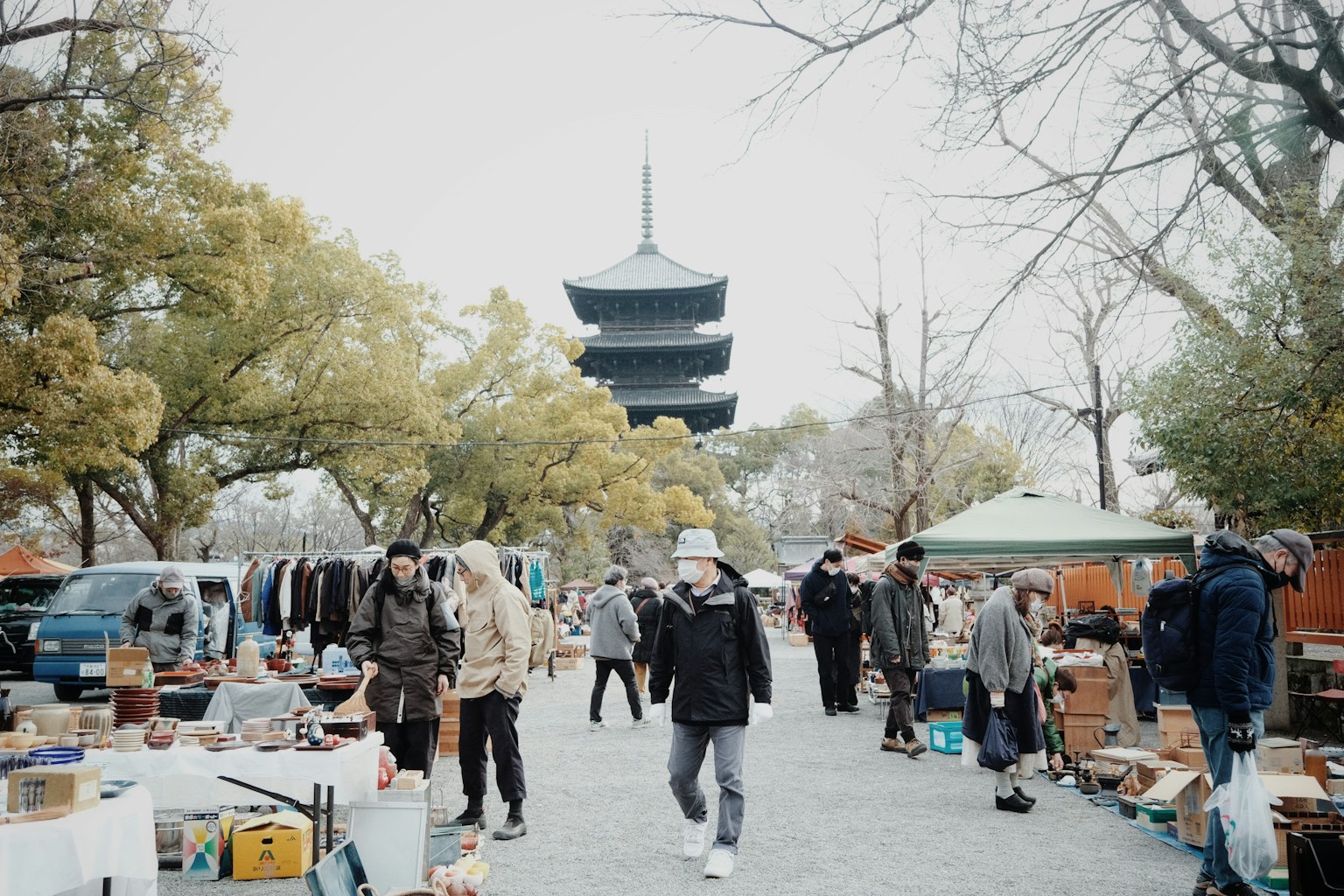 Scena di un vivace mercato delle pulci con persone che curiosano e una pagoda sullo sfondo