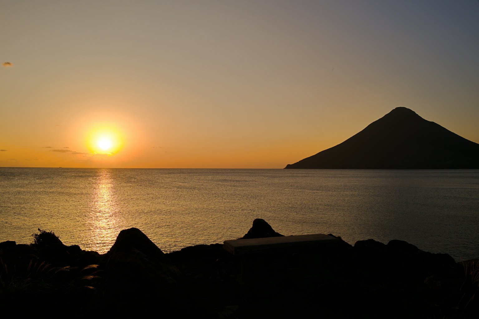 A beautiful sunset over the sea with a mountain in the distance