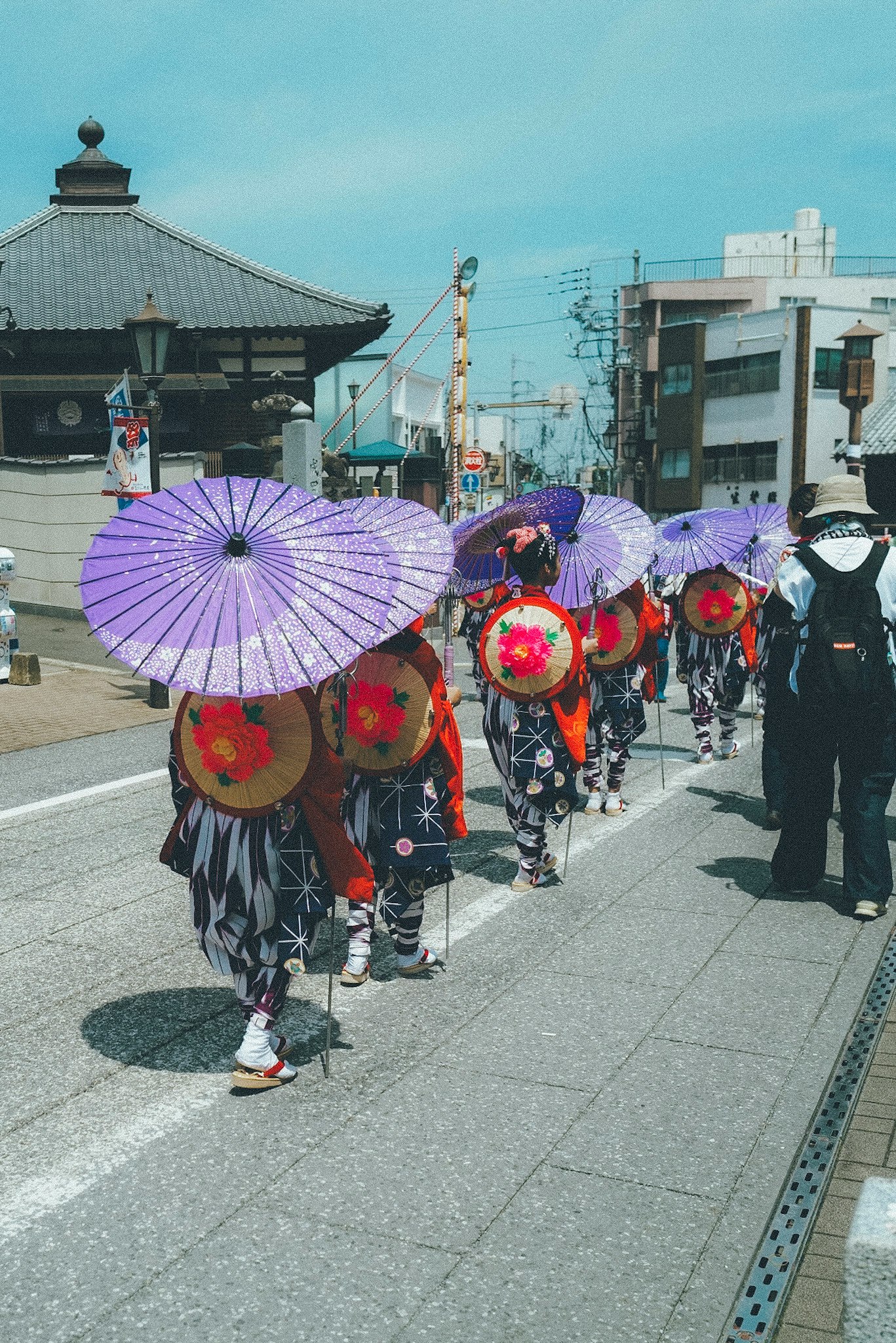 a parade of people in traditional attire holding umbrellas
