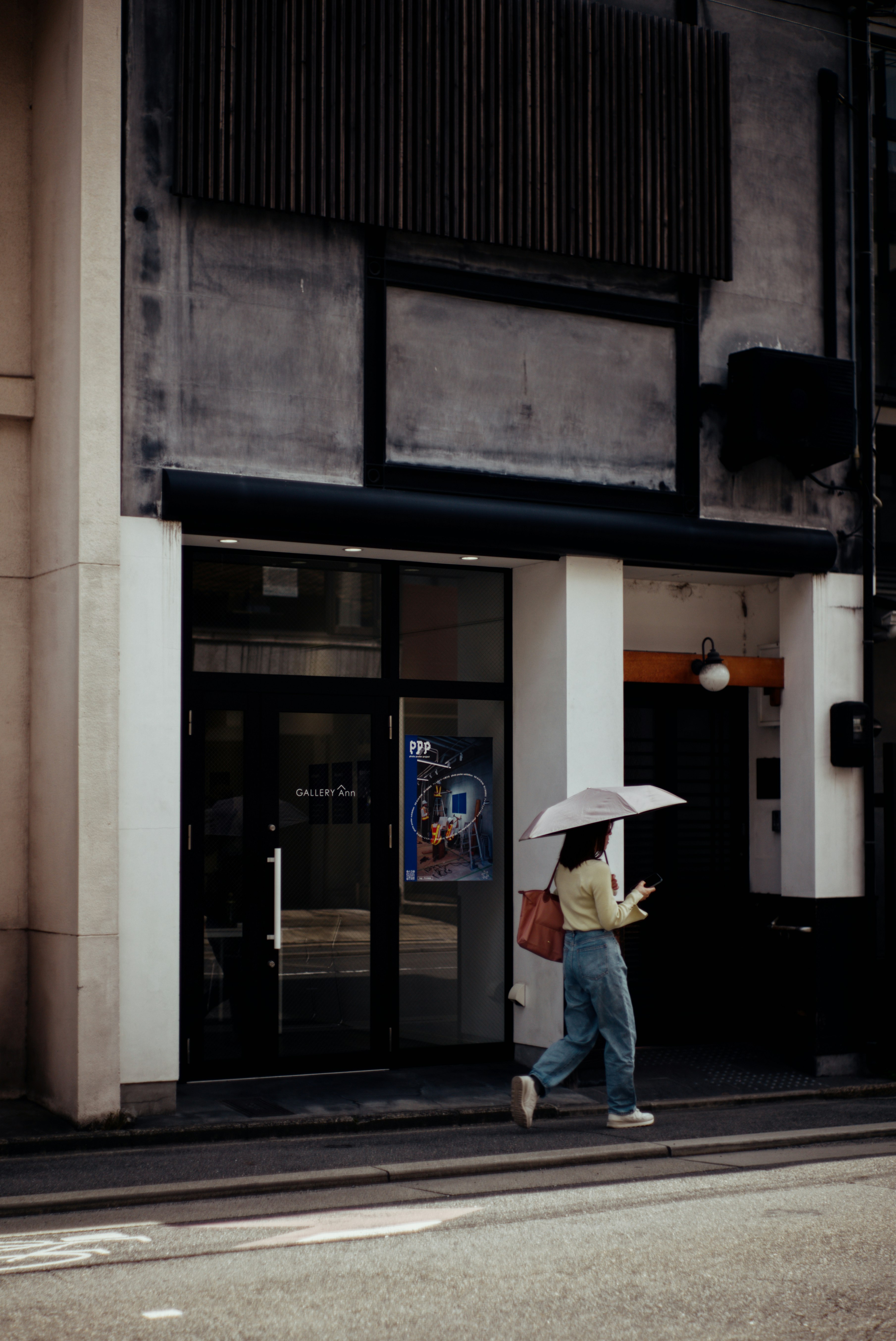 Woman walking with an umbrella in front of a modern building