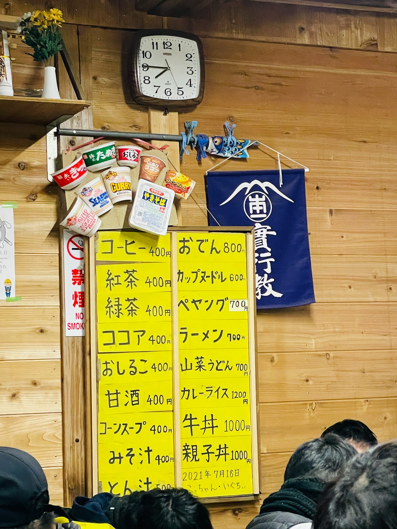Interno di un ristorante con un menu giallo su una parete di legno e un orologio