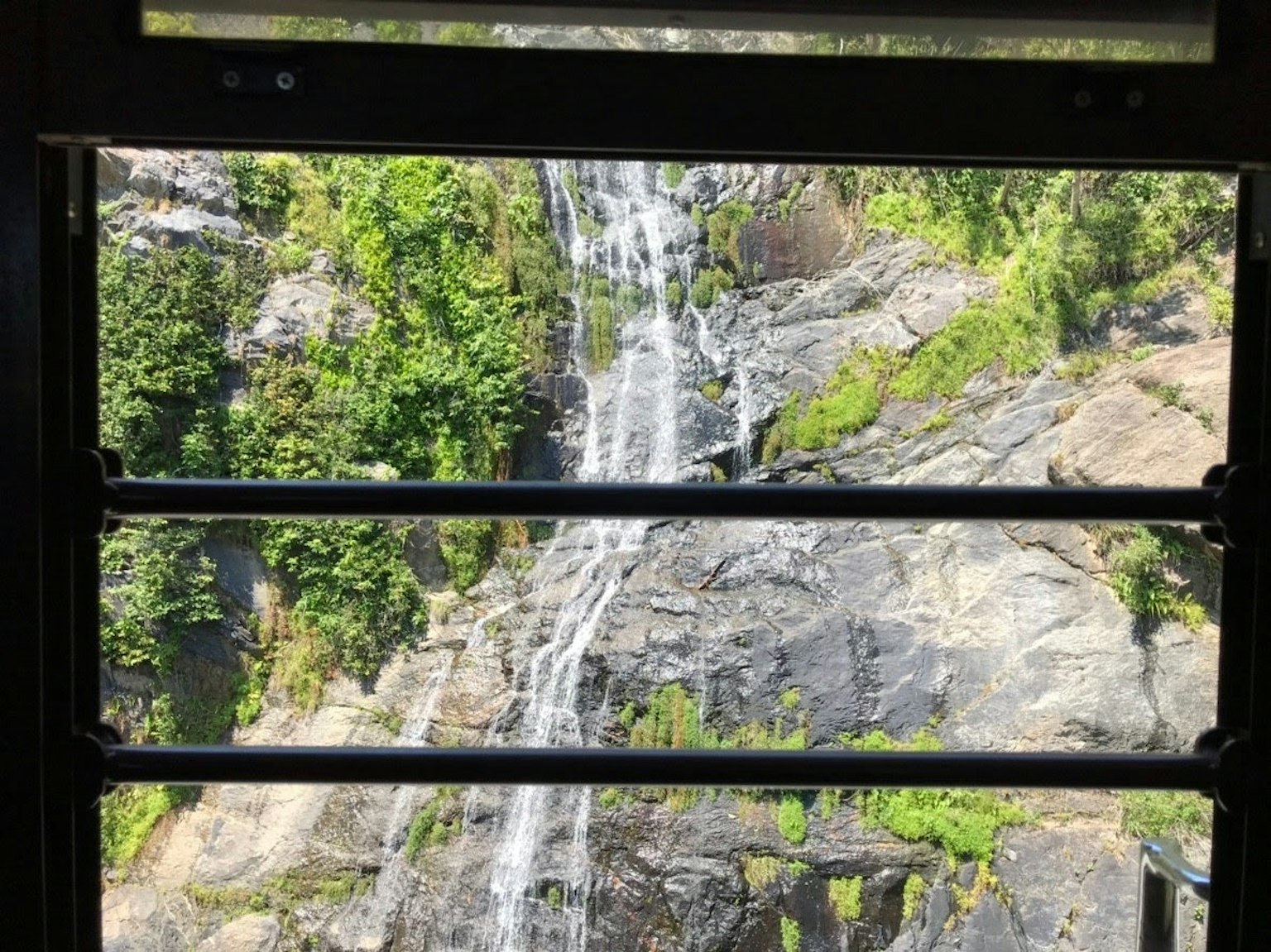 View of a waterfall and rocky greenery from a window