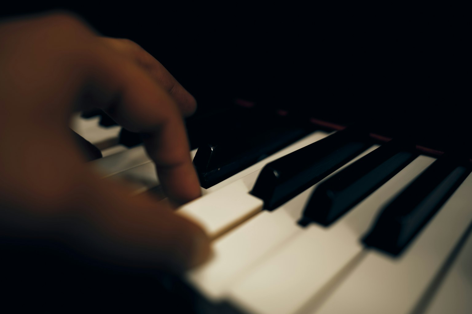Primo piano di una mano che suona i tasti del pianoforte