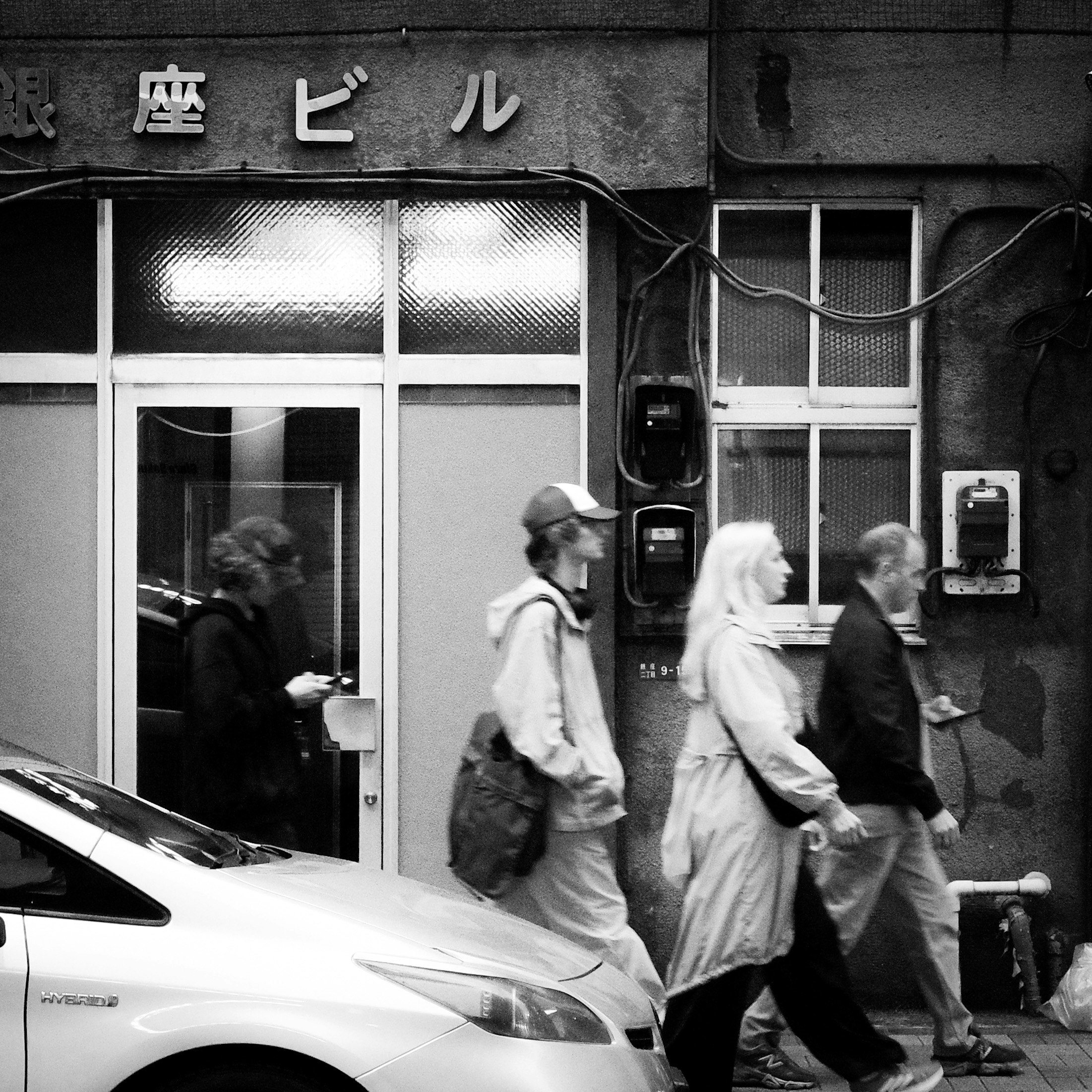 銀座の路地を歩く人々と車、モノクロの街並み