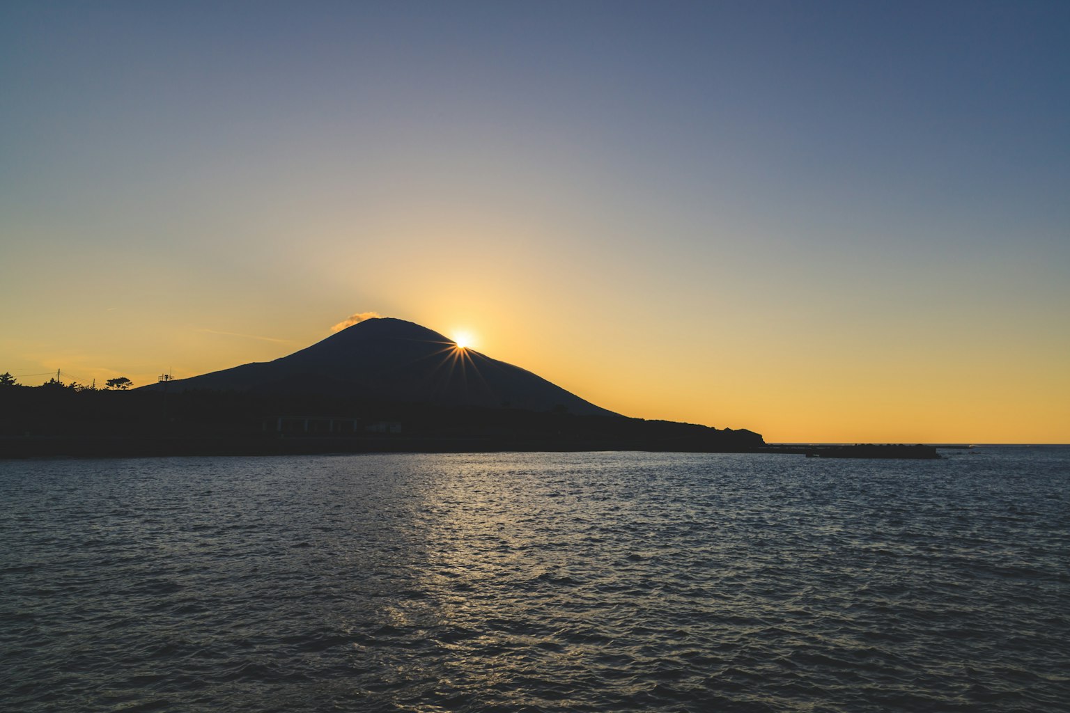 Sonnenuntergang hinter einem Berg über dem Meer