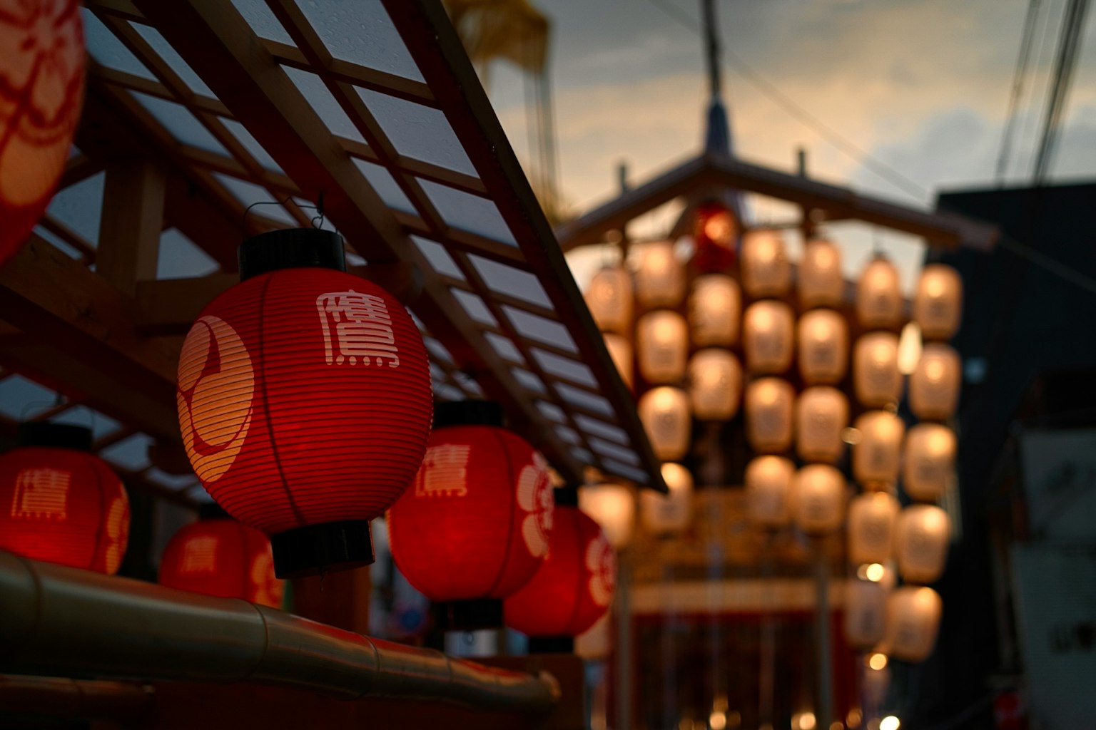 Red lanterns in a night scene with illuminated float in the background