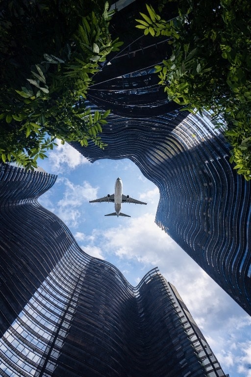 空に向かって伸びる高層ビルと飛行機のある都市の眺め