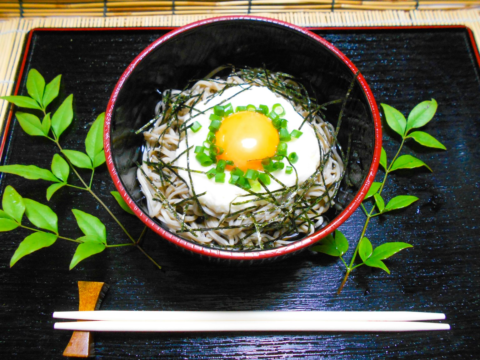 บะหมี่โซบะที่มีไข่ดิบและต้นหอมในชามสีดำ