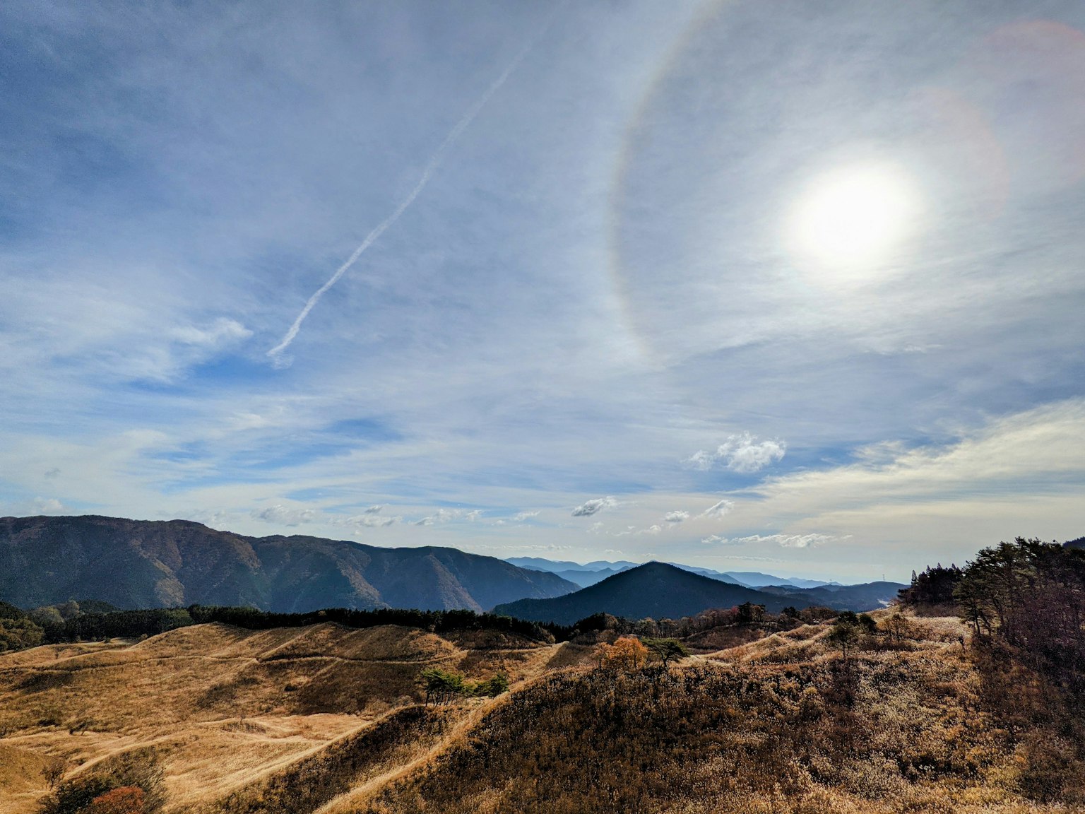 Cielo sereno con montagne e un alone arcobaleno attorno al sole