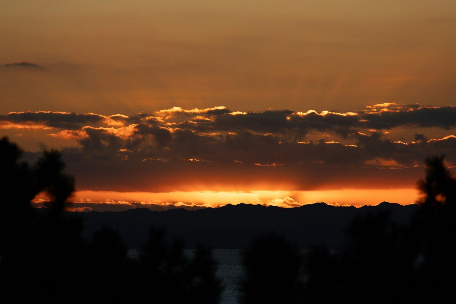 Bellissimo paesaggio al tramonto con silhouette di montagne e cielo arancione