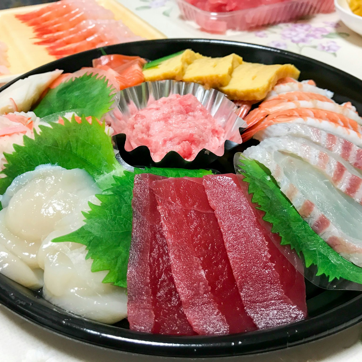 Una bandeja de sashimi colorido bellamente presentada con atún y vieiras