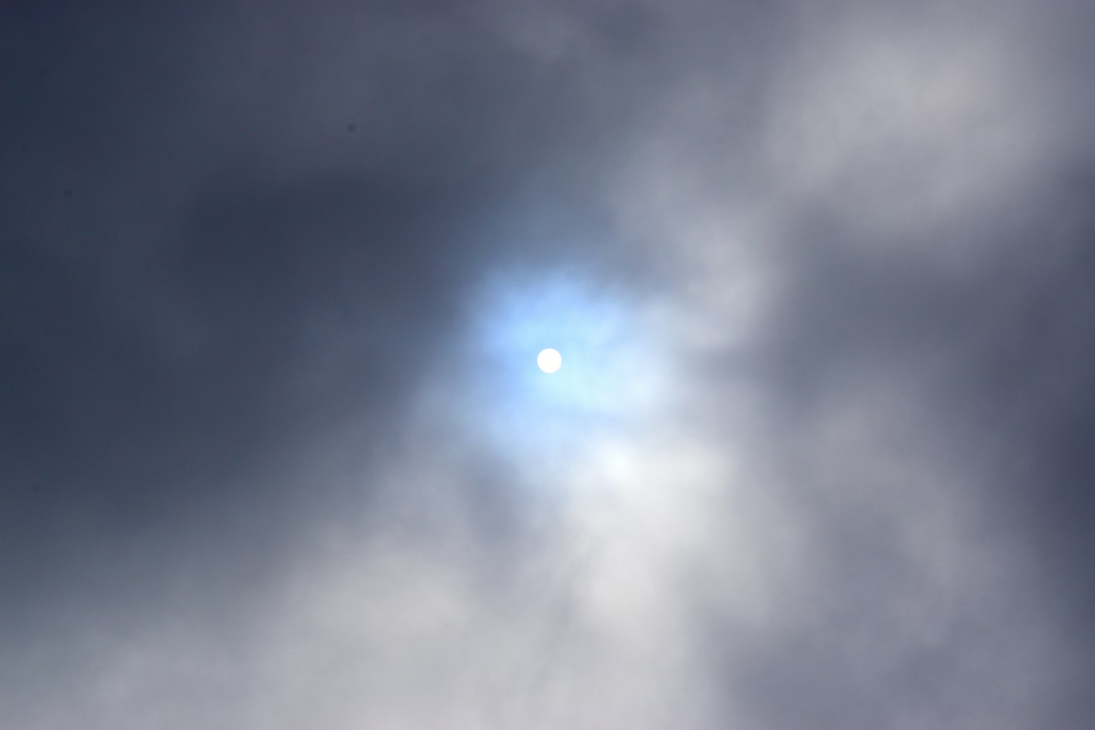 Matahari terlihat melalui awan dengan cahaya biru