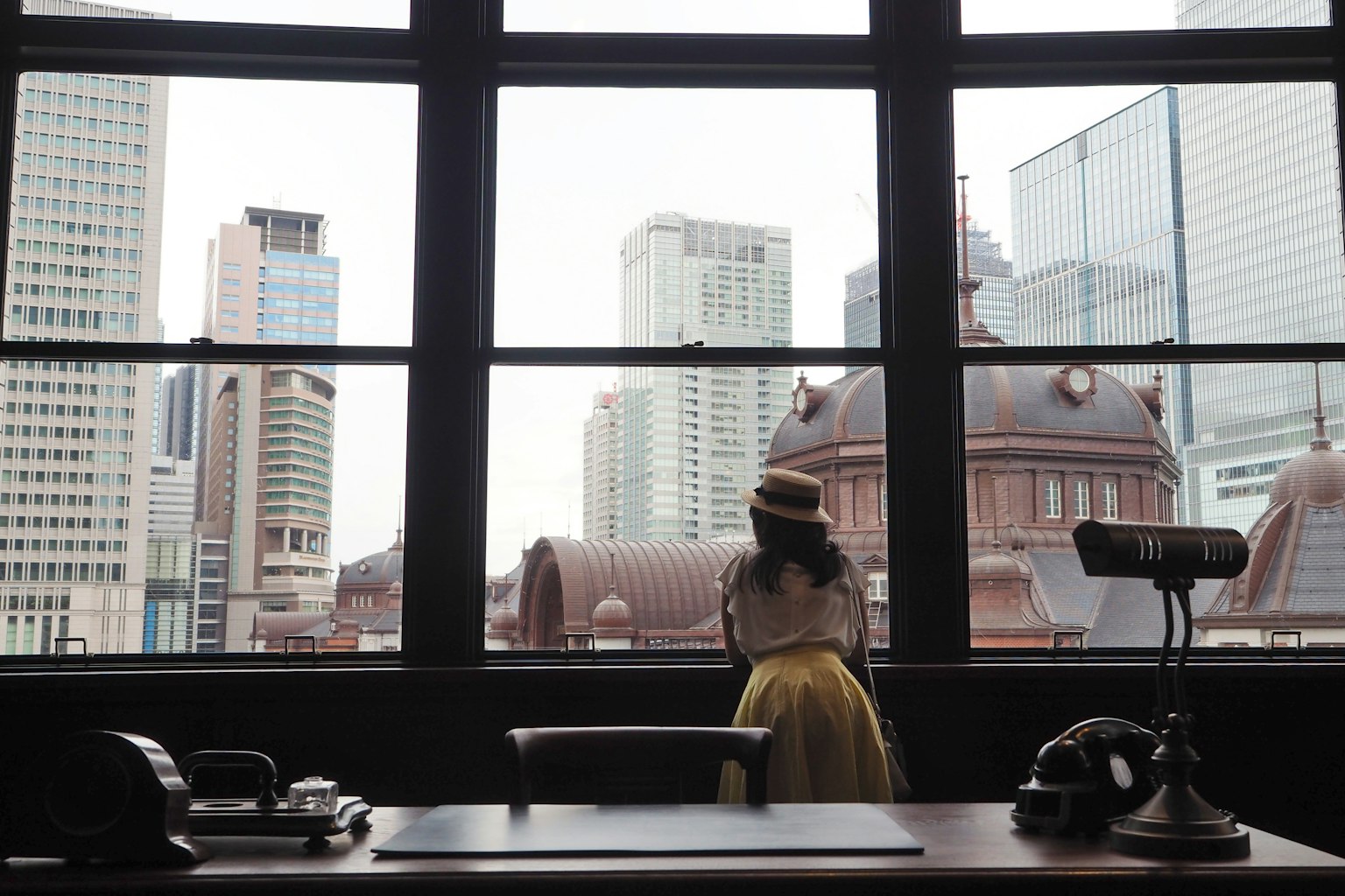 Eine Frau, die aus dem Fenster schaut mit Blick auf die Stadt