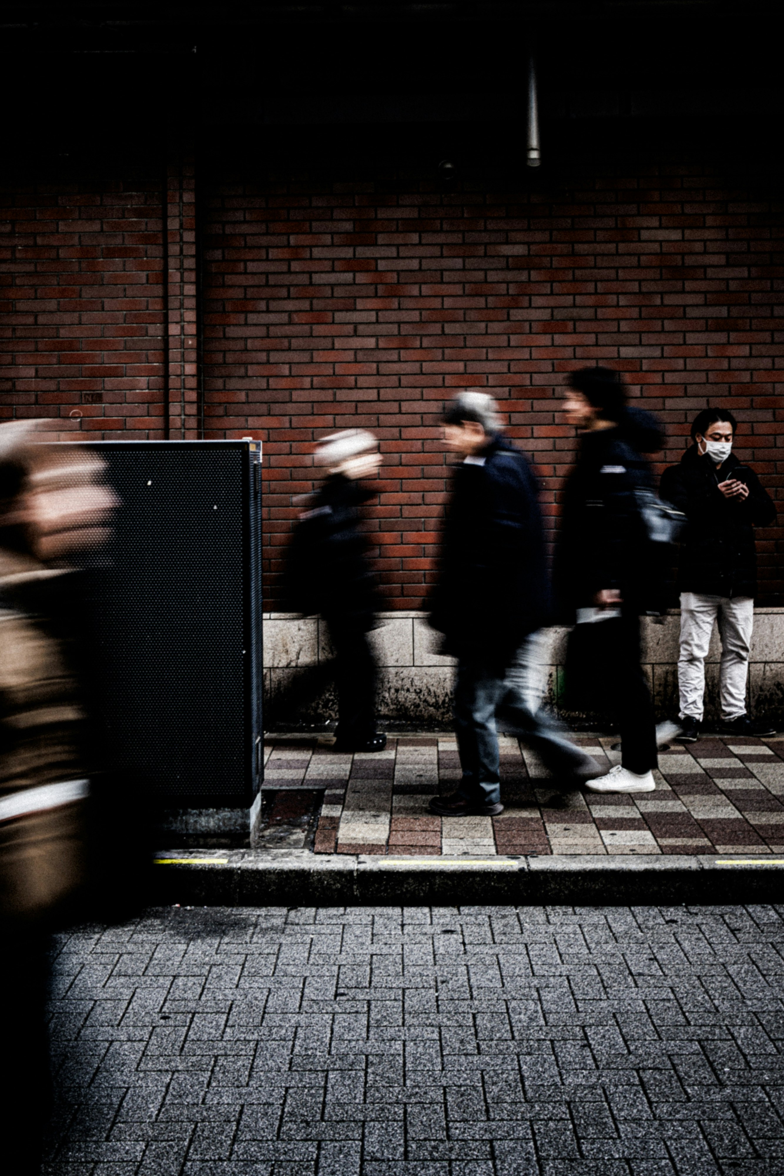 人々が歩いている街の風景 暗いレンガの壁と舗装された道
