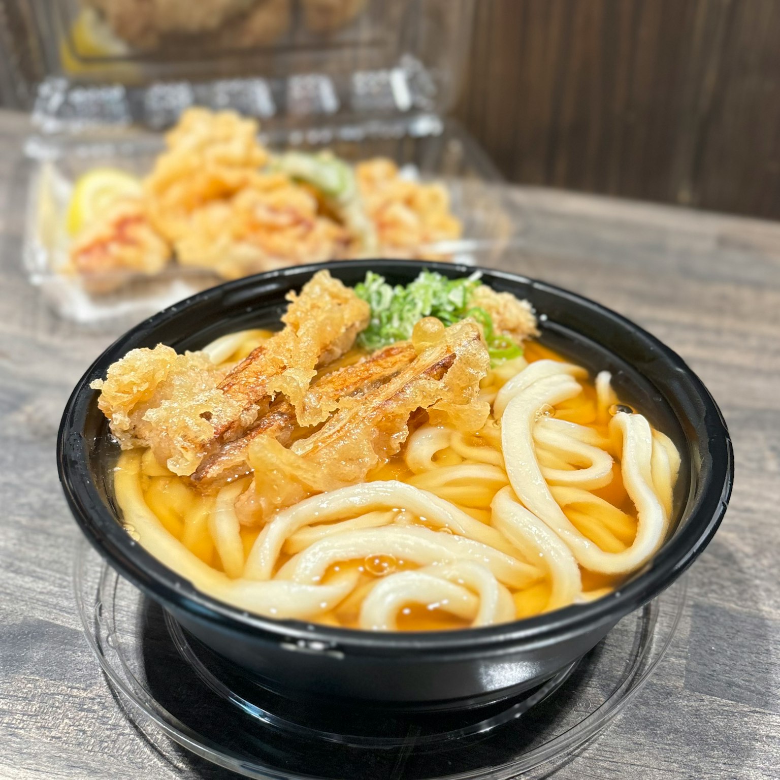 Una ciotola di noodles udon con tempura e cipollotti