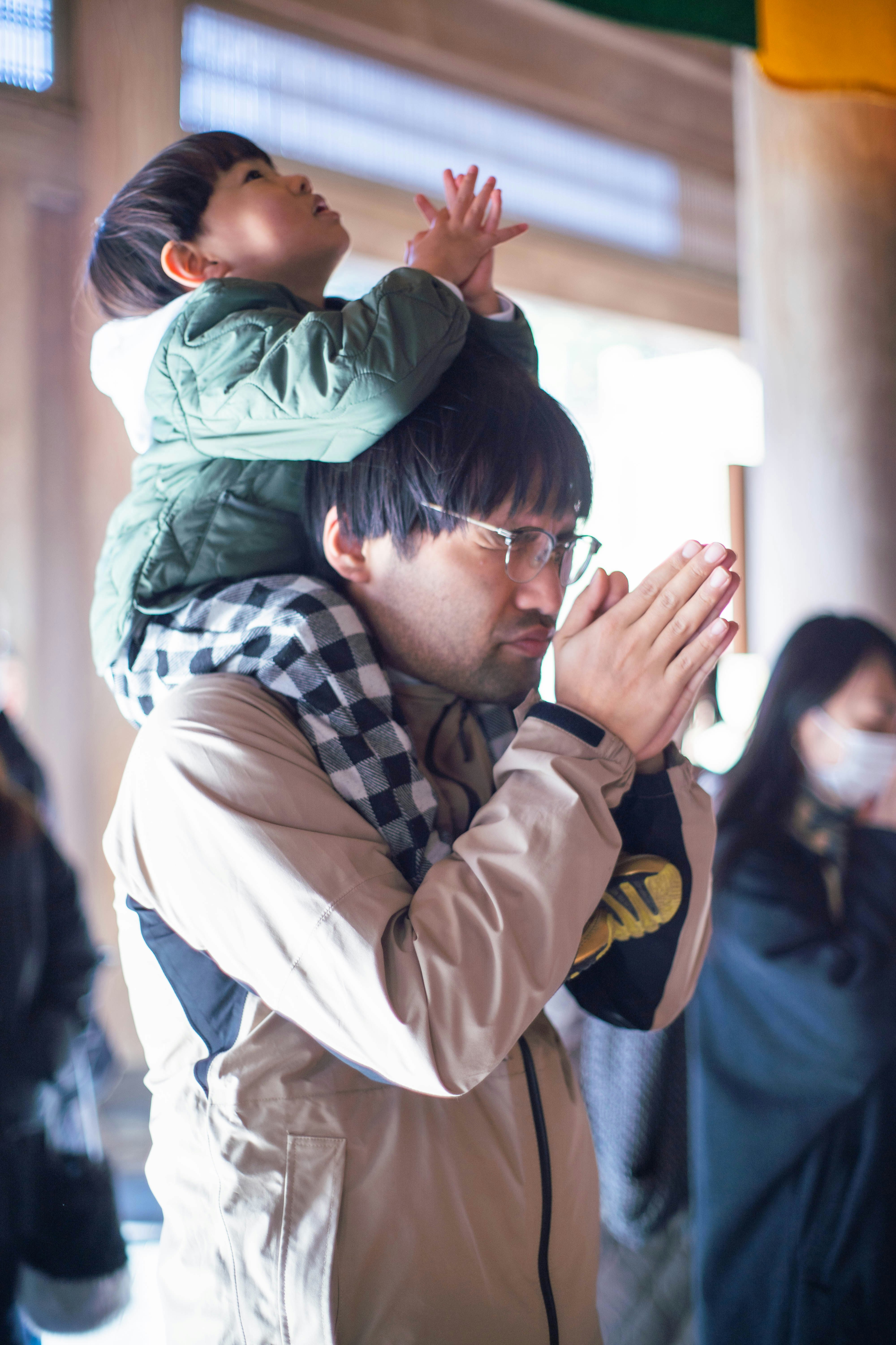 抱き上げられた子どもと見守る大人の手のある室内の場面