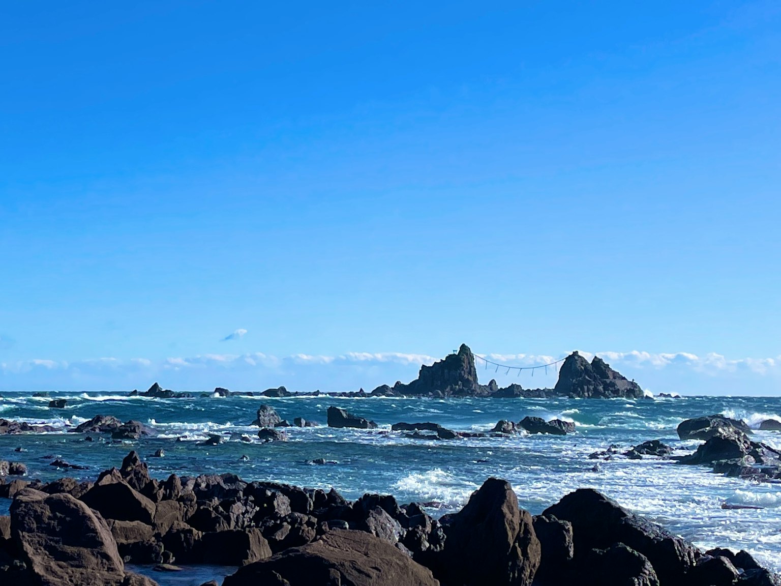 Paisaje con islas rocosas rodeadas de cielo azul y olas del océano