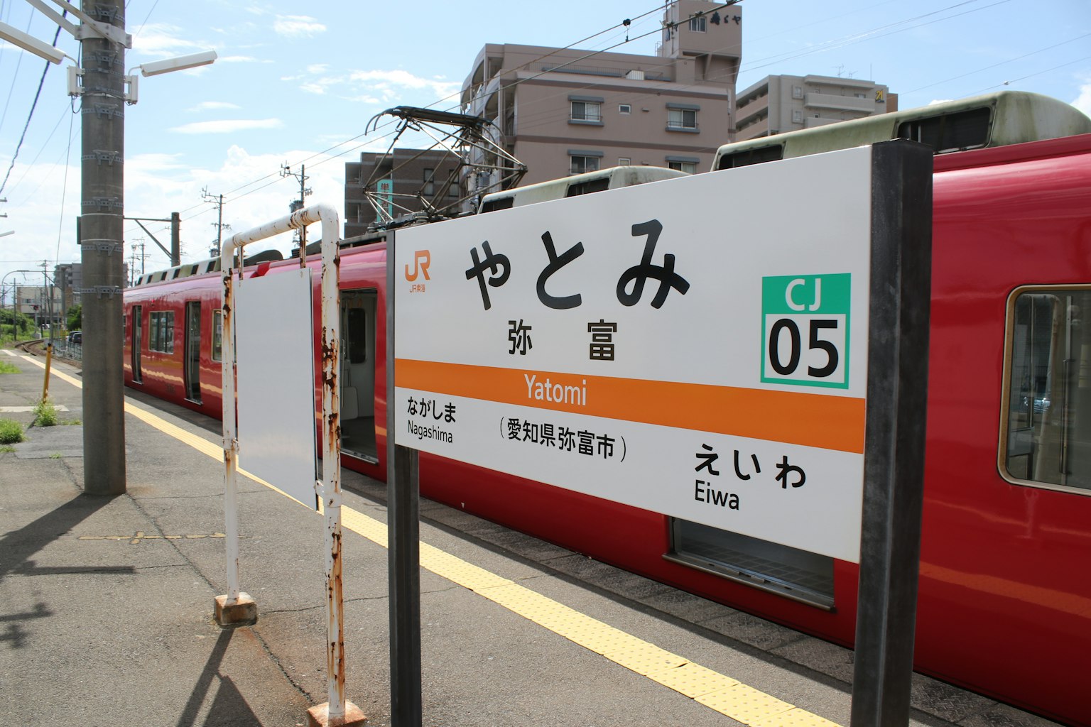 矢冢站的标志，背景有一列红色火车