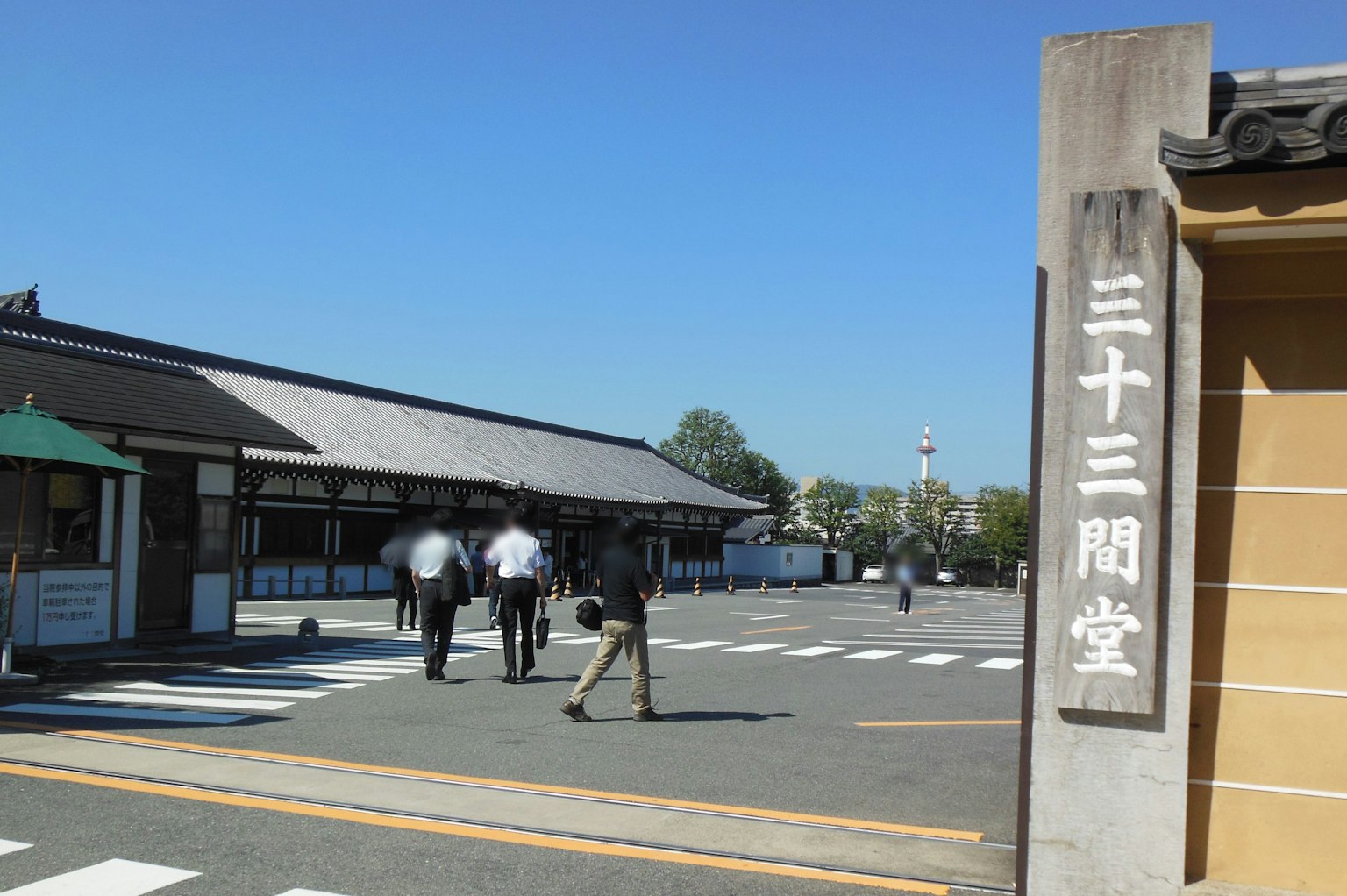 Entrance of Sanjusangendo with people walking under a blue sky