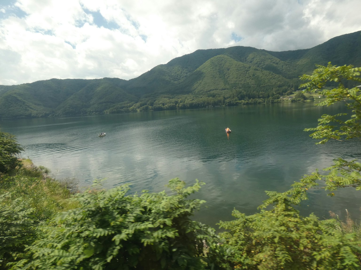 Lac serein entouré de montagnes verdoyantes sous un ciel nuageux