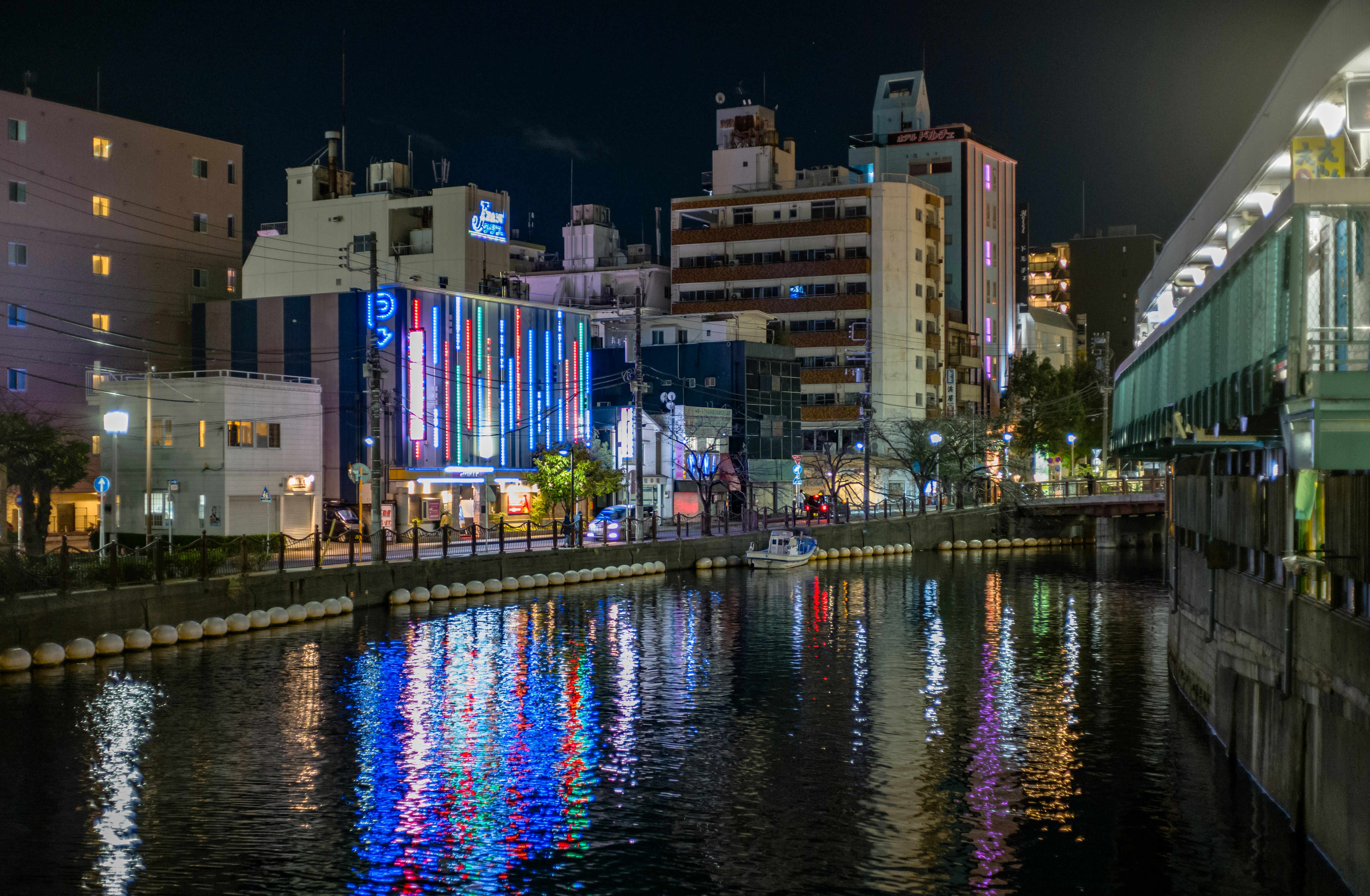 夜の運河沿いに並ぶ高層ビルとネオンの光
