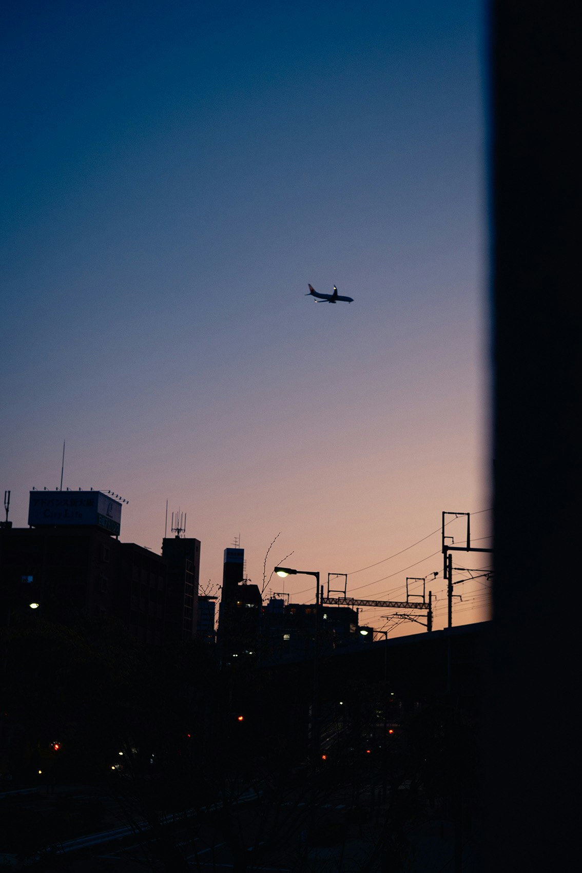 夕焼け空に飛行機が浮かぶ夜明け前の街並み