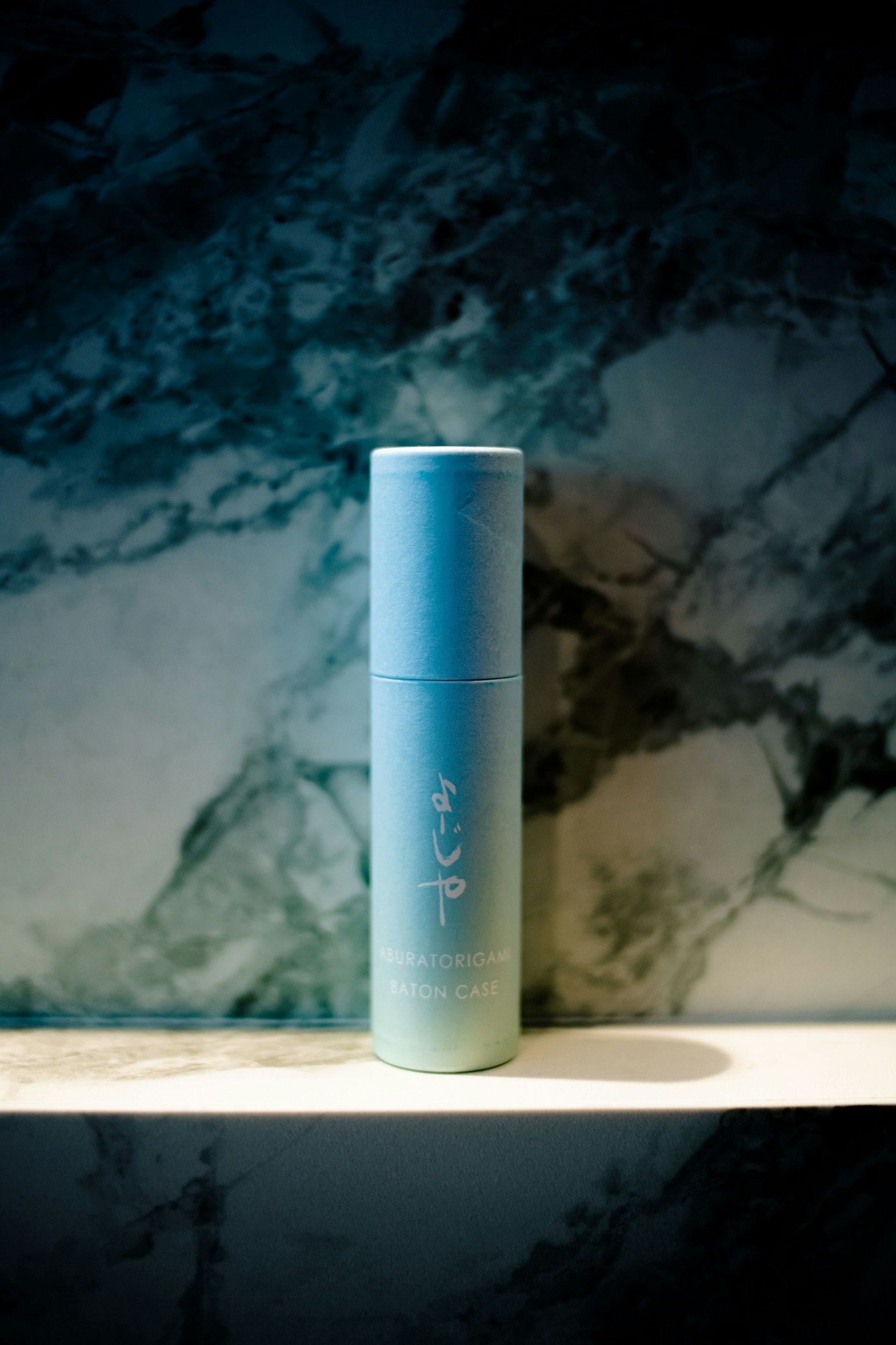 Flasche mit Farbverlauf von Blau zu Grün vor einem Marmorhintergrund