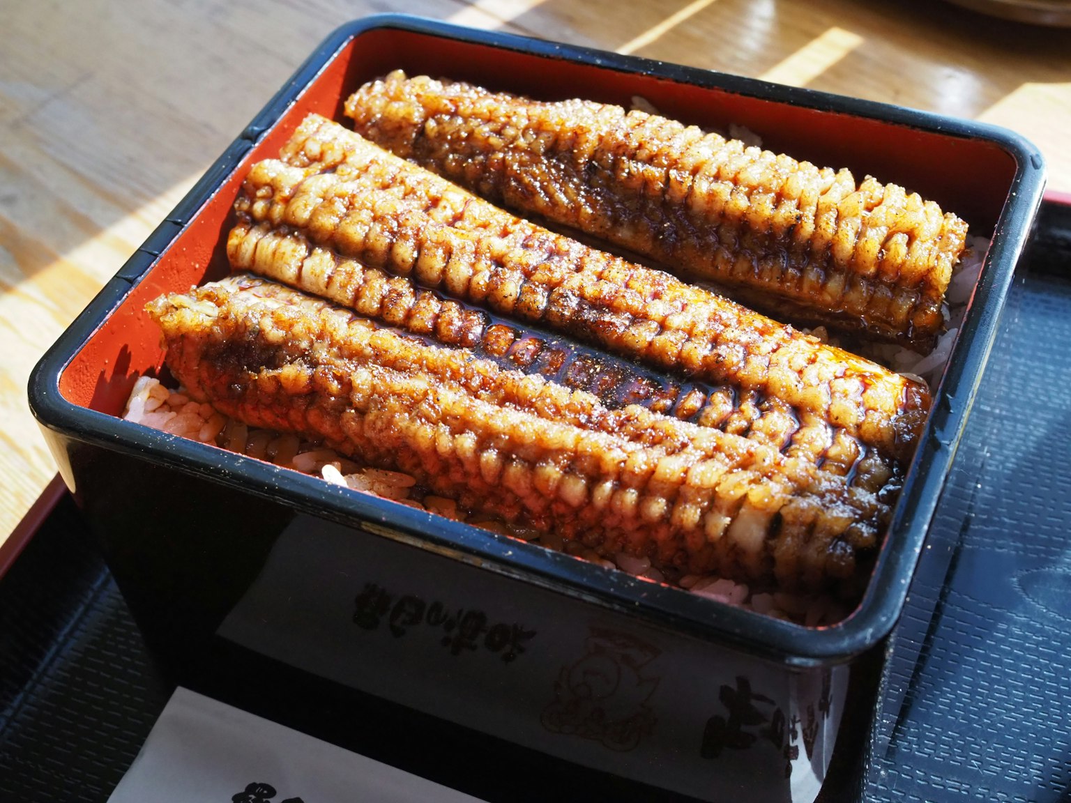 Une boîte à bento contenant de l'anguille grillée avec un glaçage brillant