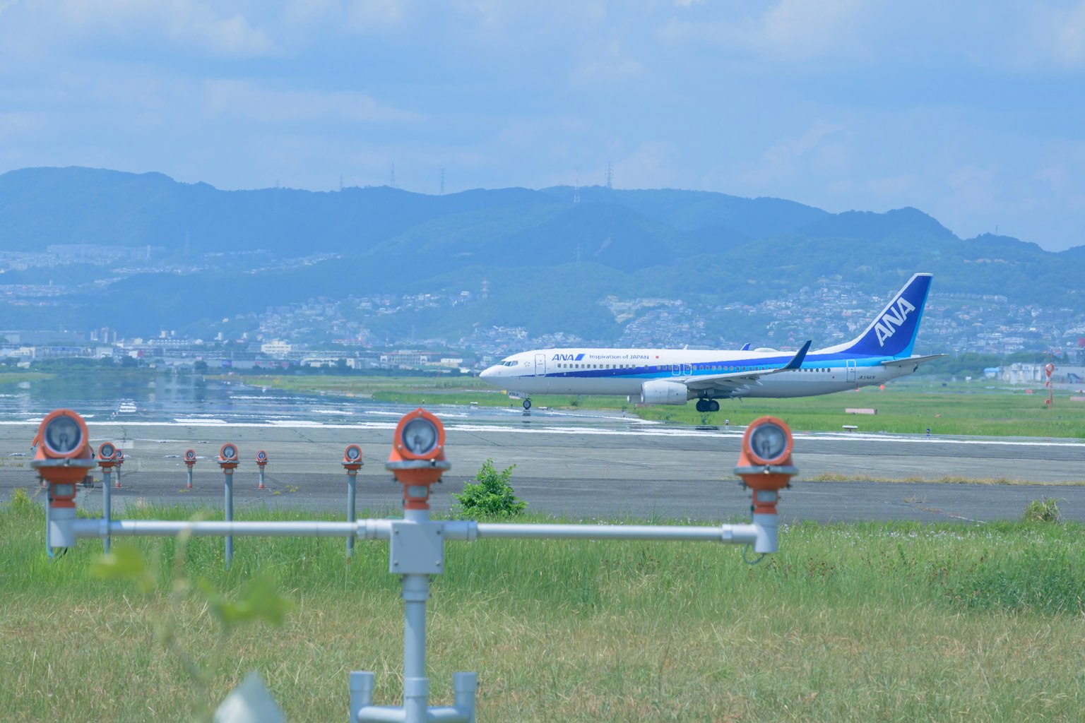Airplane taxiing on runway with mountains in the background