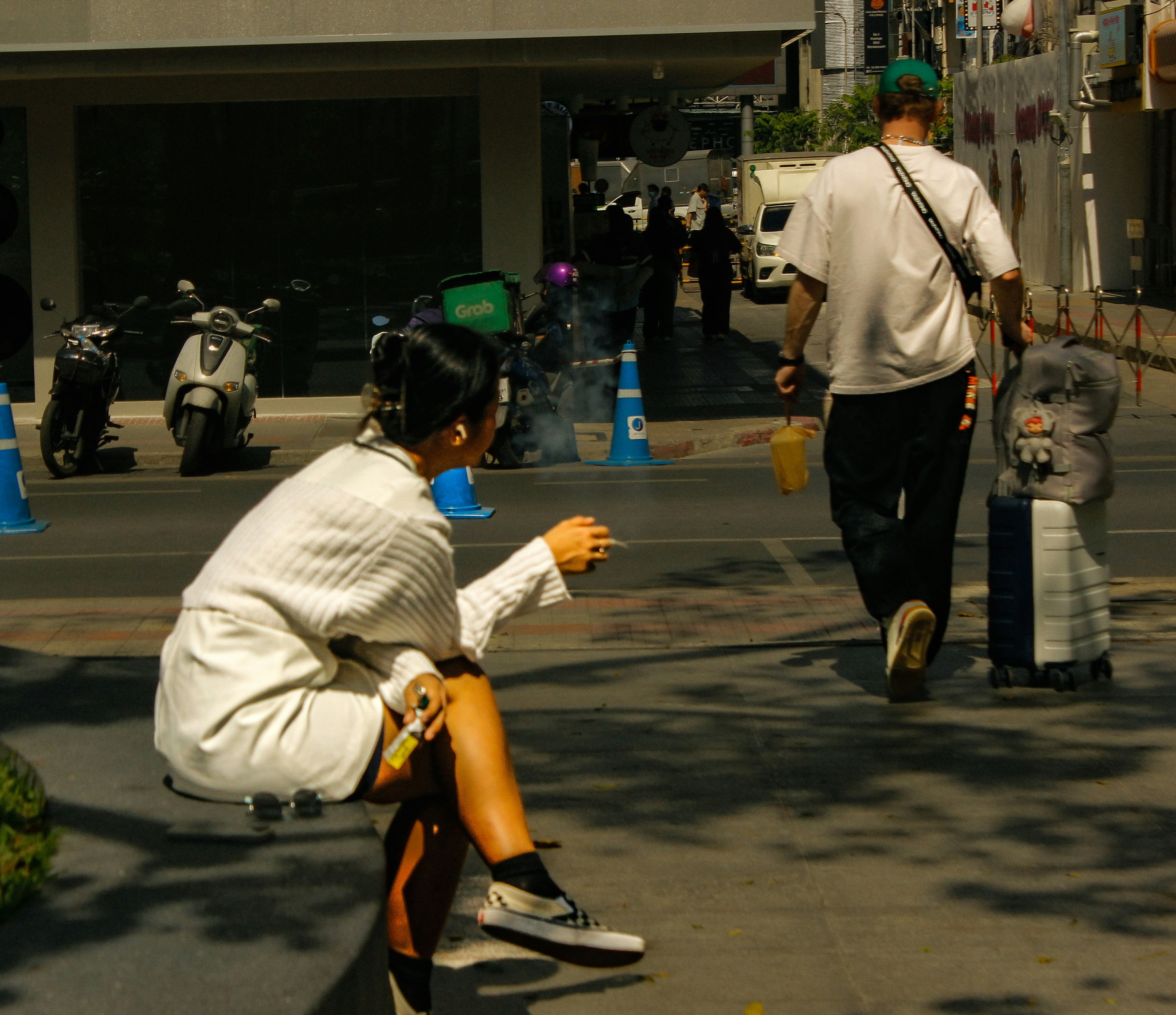 街角で座っている女性と歩いている男性のシーン