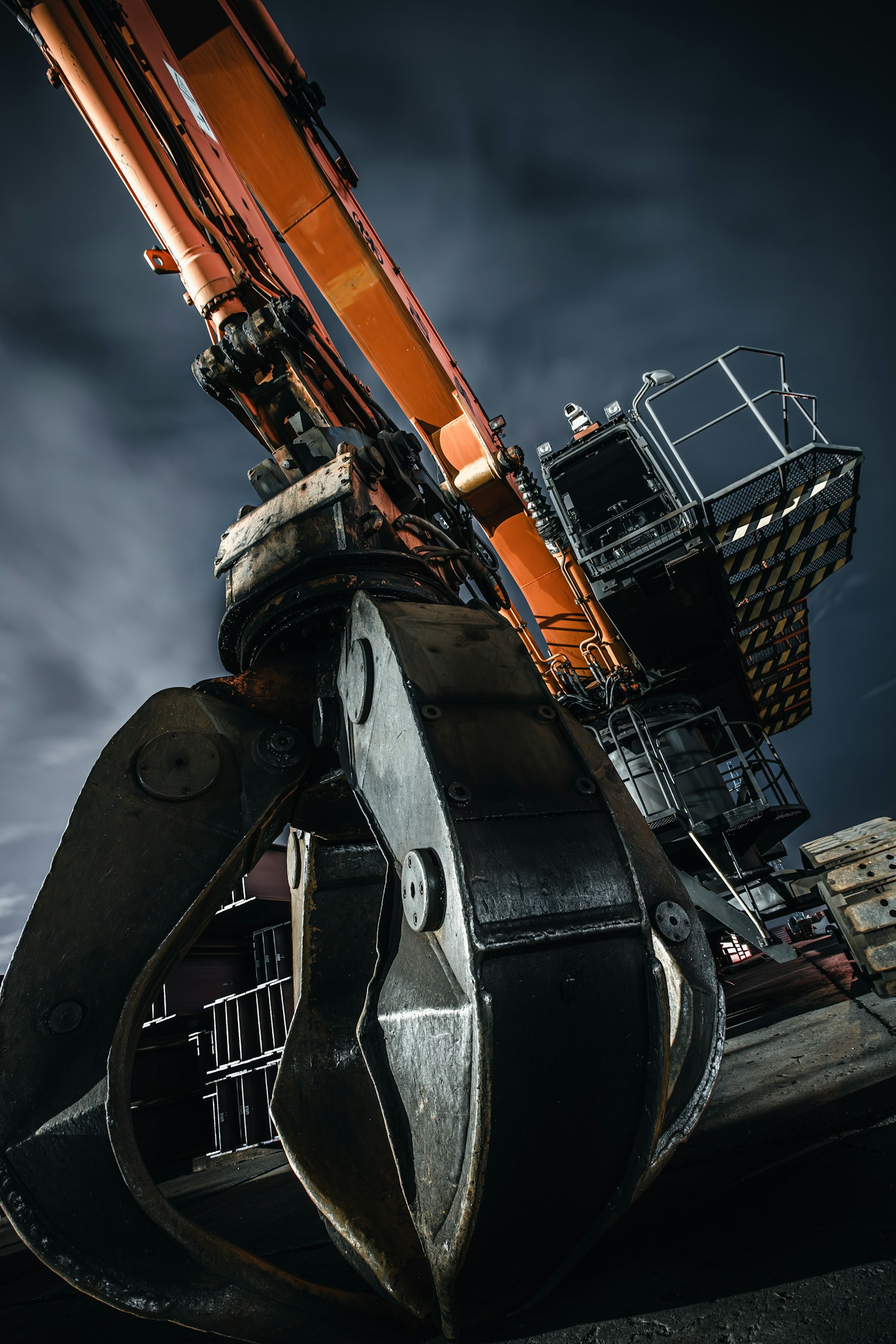 クレーンのクローとオレンジ色のアームが特徴的な工事現場の画像