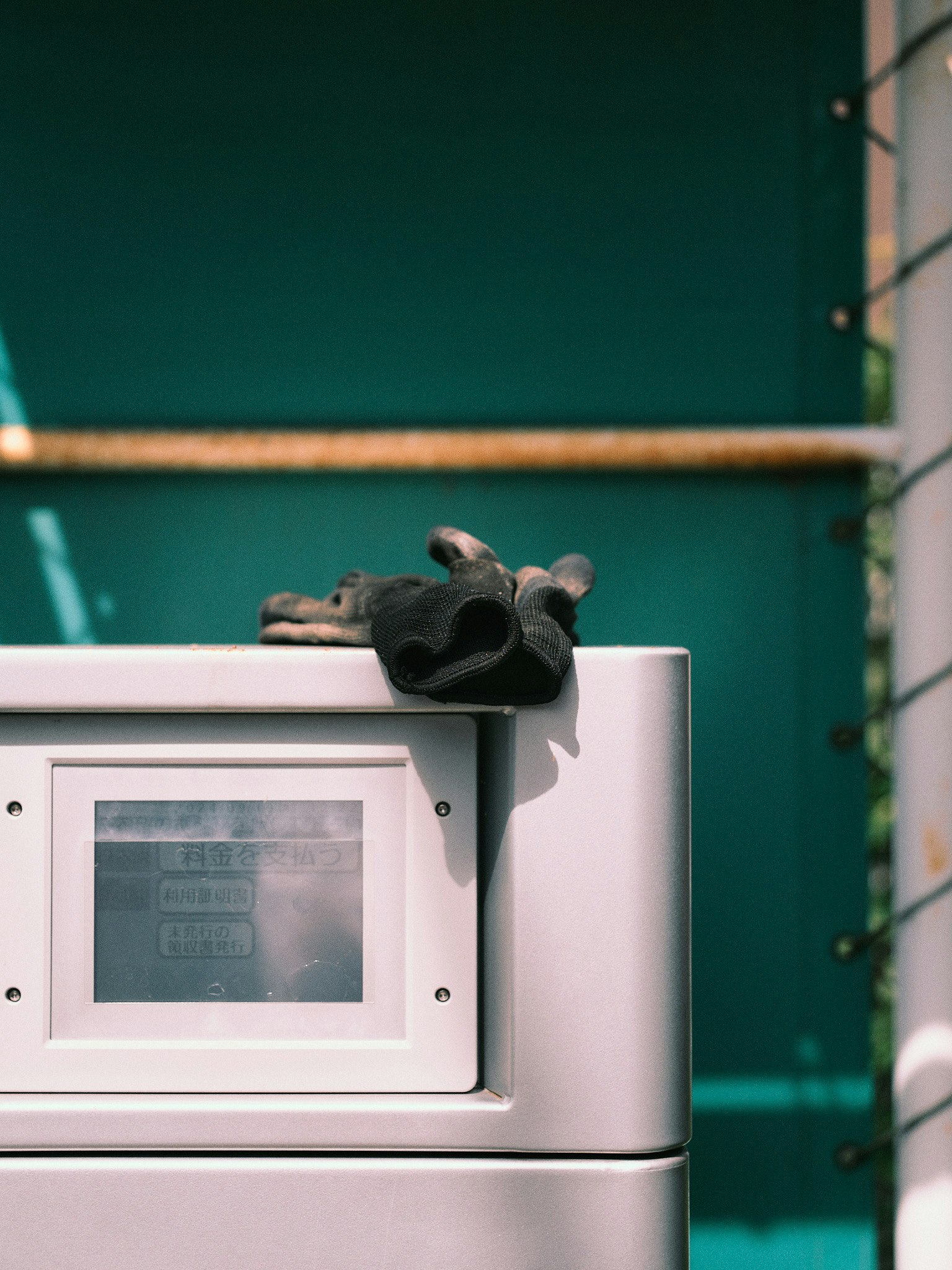 Gray box with a black glove resting on top against a green background