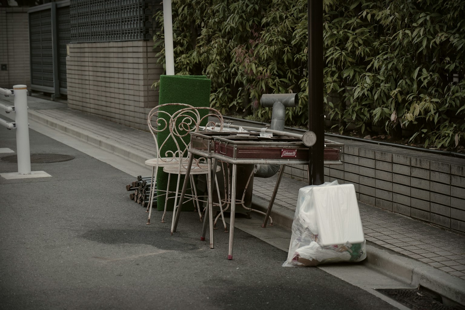 An old table and chair set placed on the street with a garbage bag