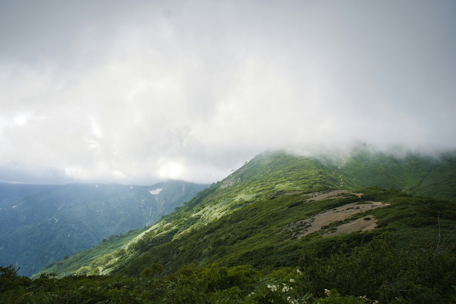 Üppige grüne Berglandschaft mit bewölktem Himmel
