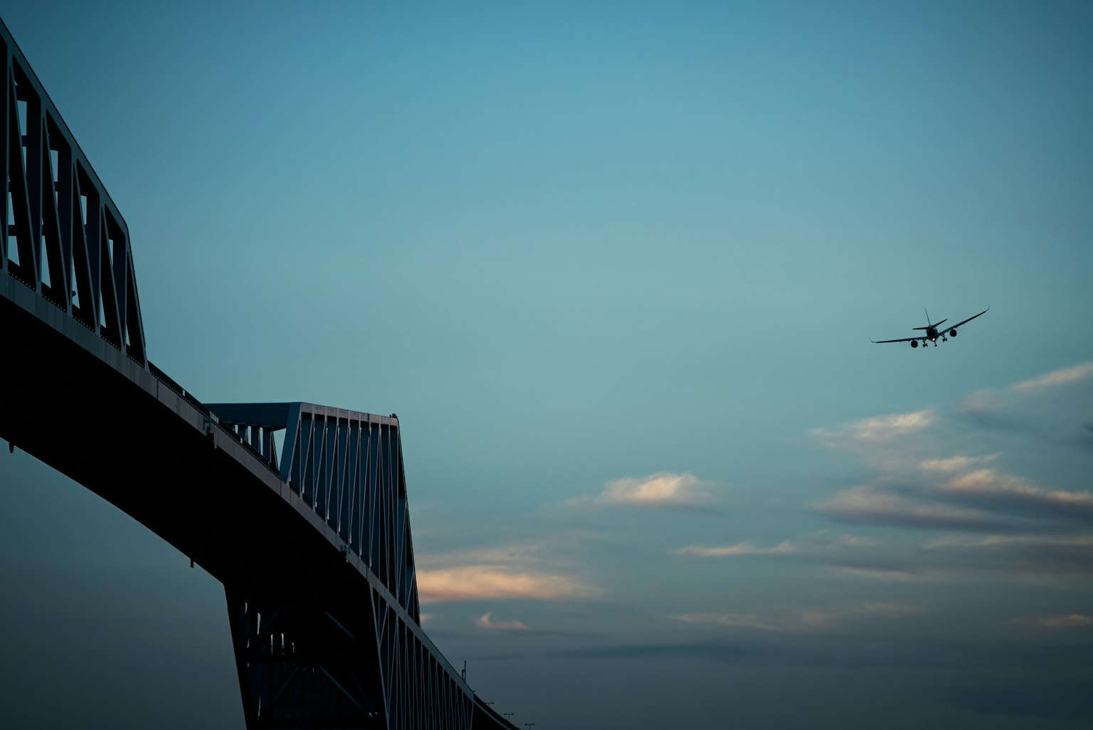 Blick auf eine Brücke in der Nähe eines Flughafens mit einem fliegenden Flugzeug