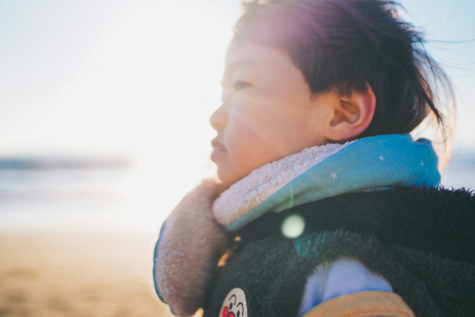 Side profile of a child with wind-blown hair at the beach