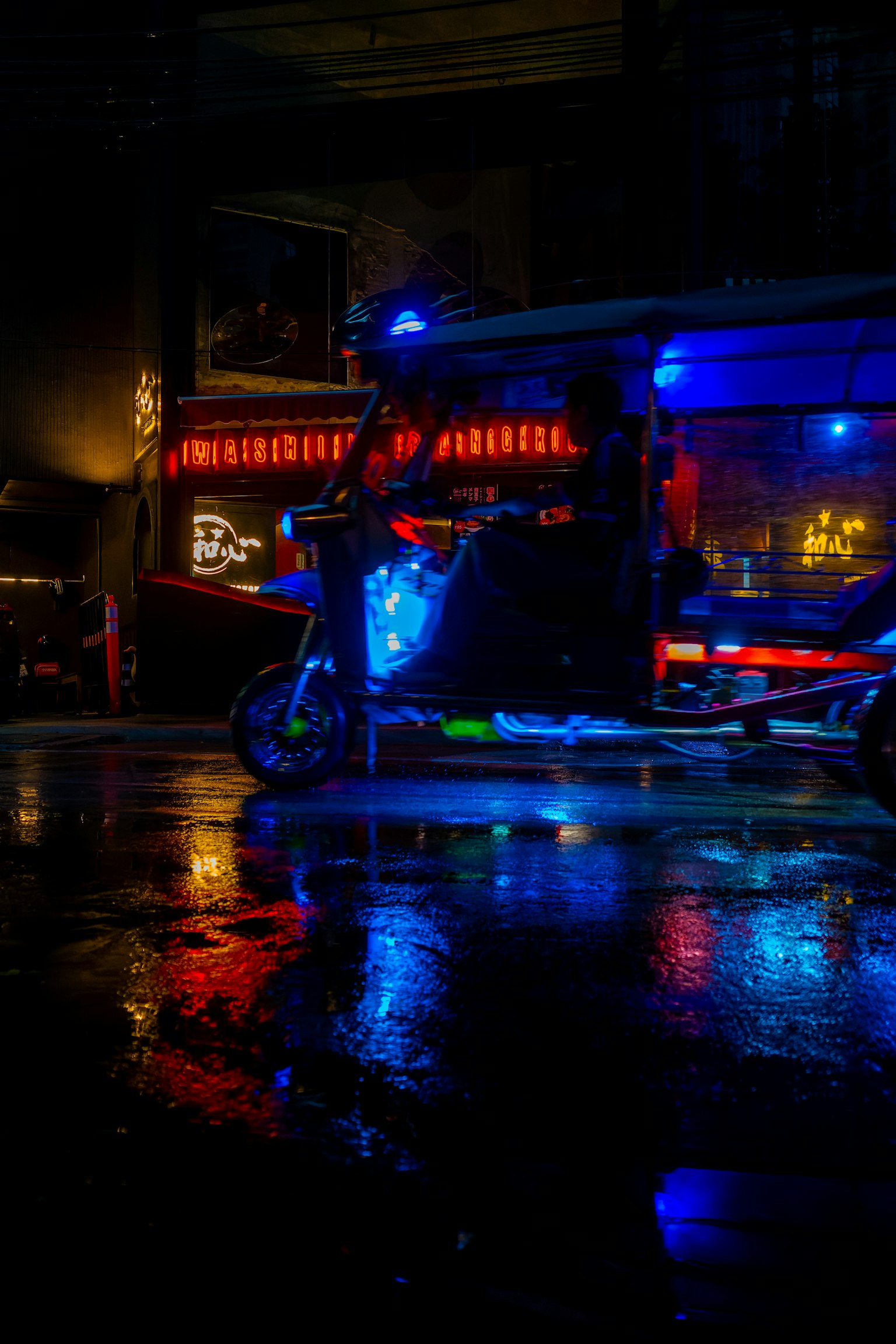 비 오는 도시 환경에서 파란 불빛으로 조명된 스쿠터와 반사