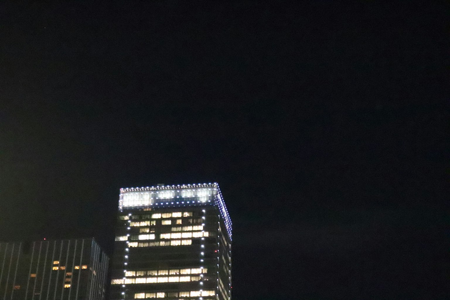 La parte superiore di un grattacielo illuminata contro il cielo notturno
