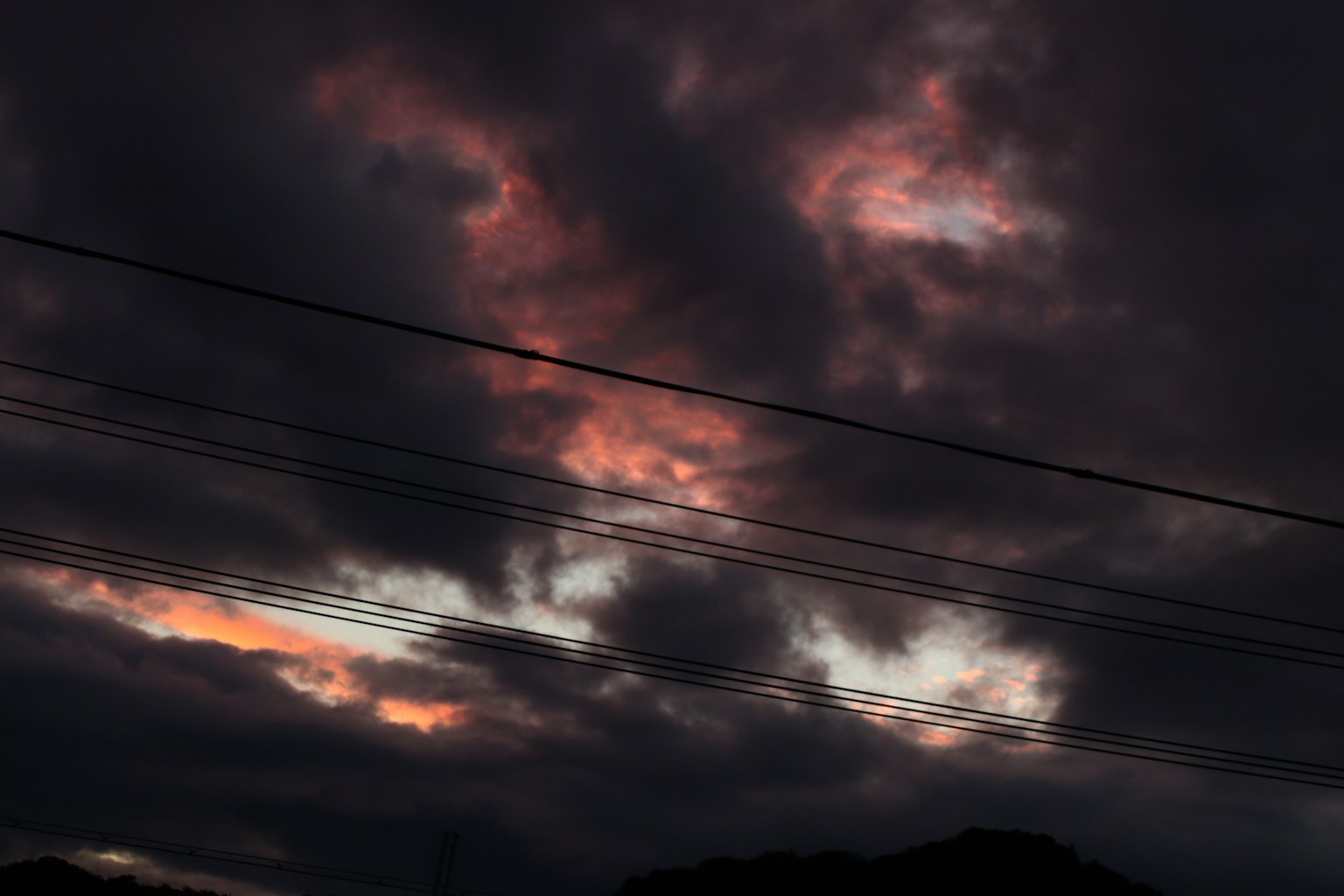 Dramatischer Himmel mit dunklen Wolken und lebhaften Orange- und Rosatönen bei Sonnenuntergang
