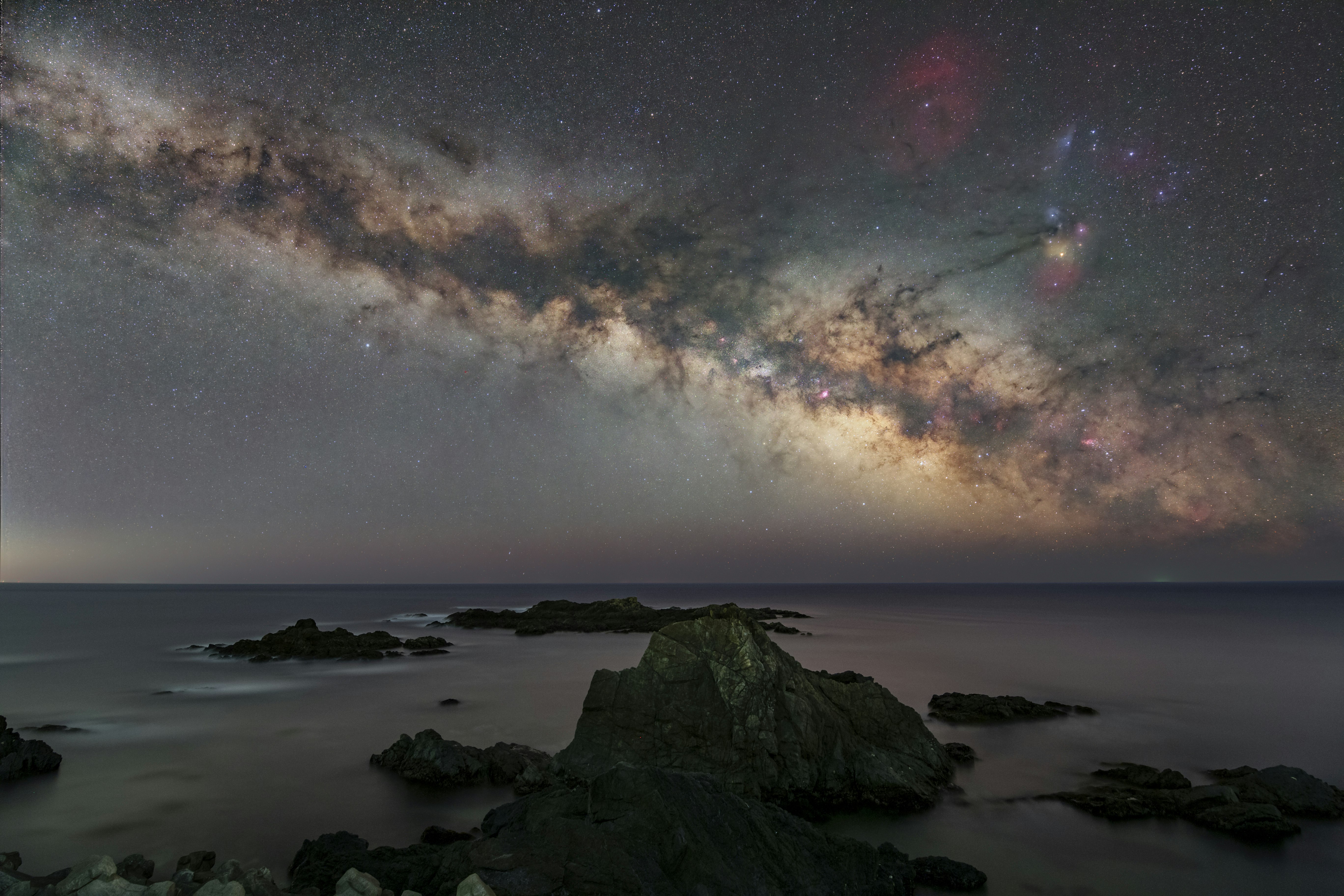 岩礁のある海岸と天の川が広がる夜空
