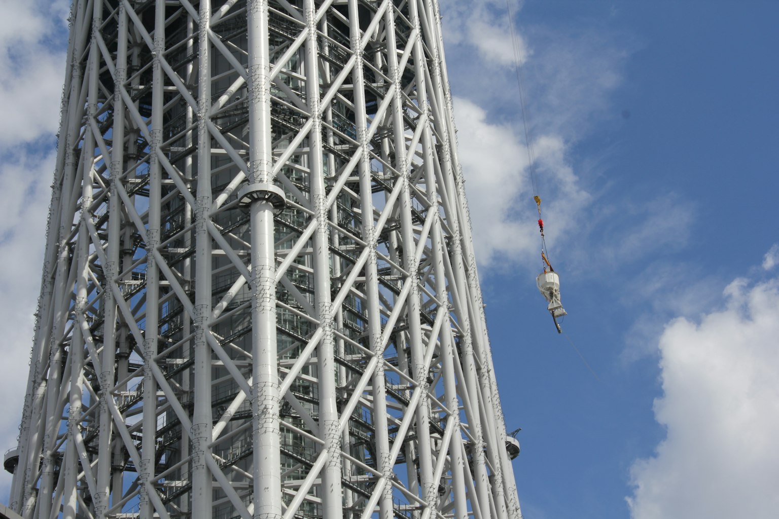 Estructura de la Tokyo Skytree con un trabajador suspendido bajo un cielo azul