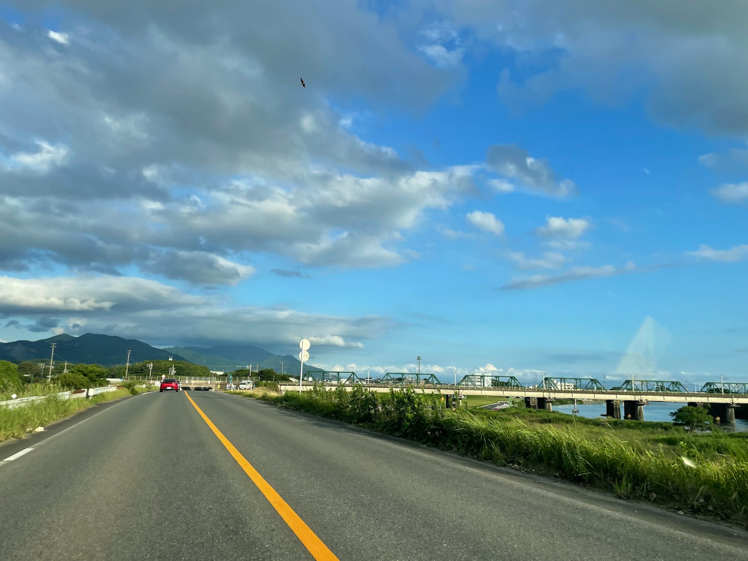 Scenic road with a blue sky and clouds alongside a river