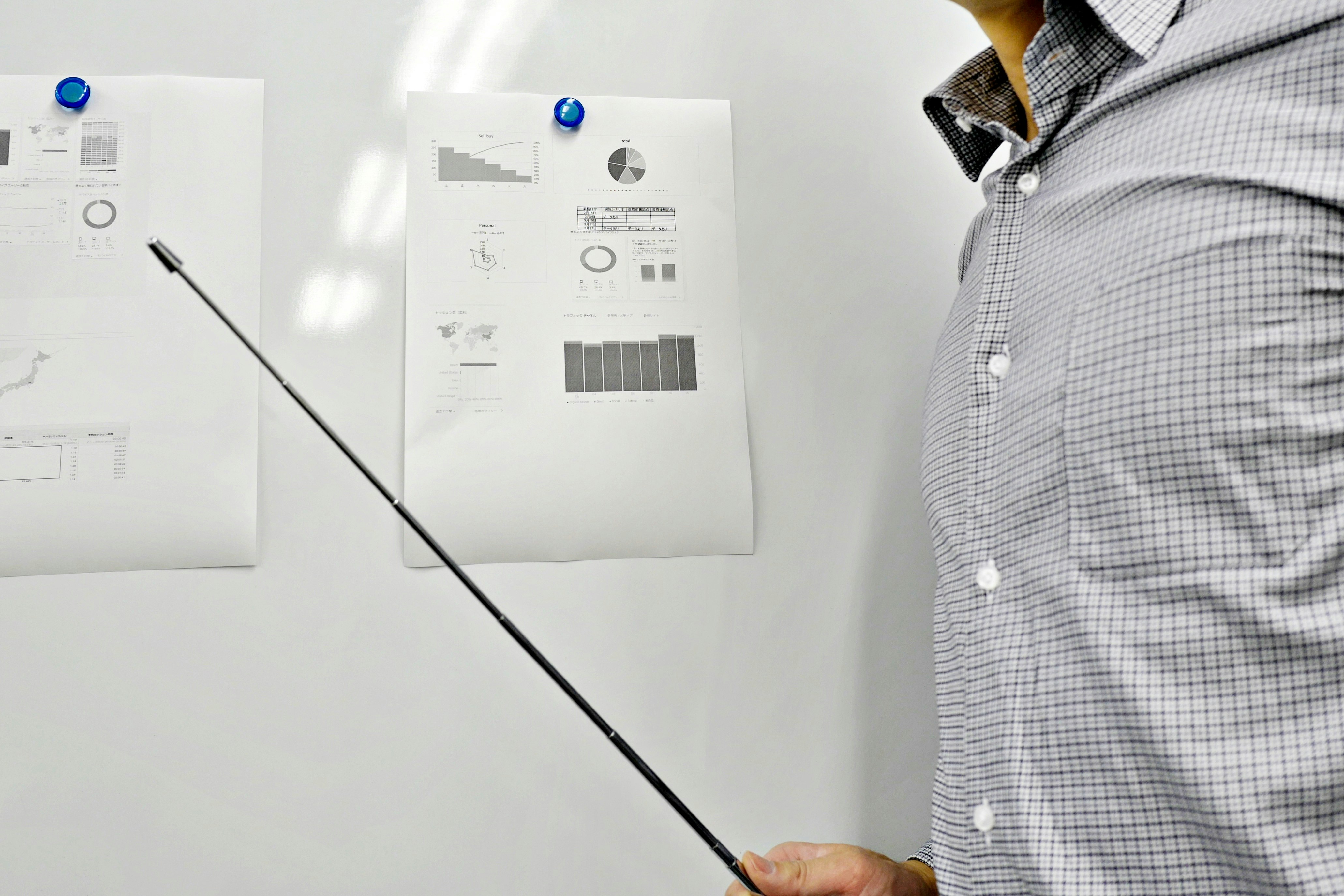 person pointing at documents in front of a white wall
