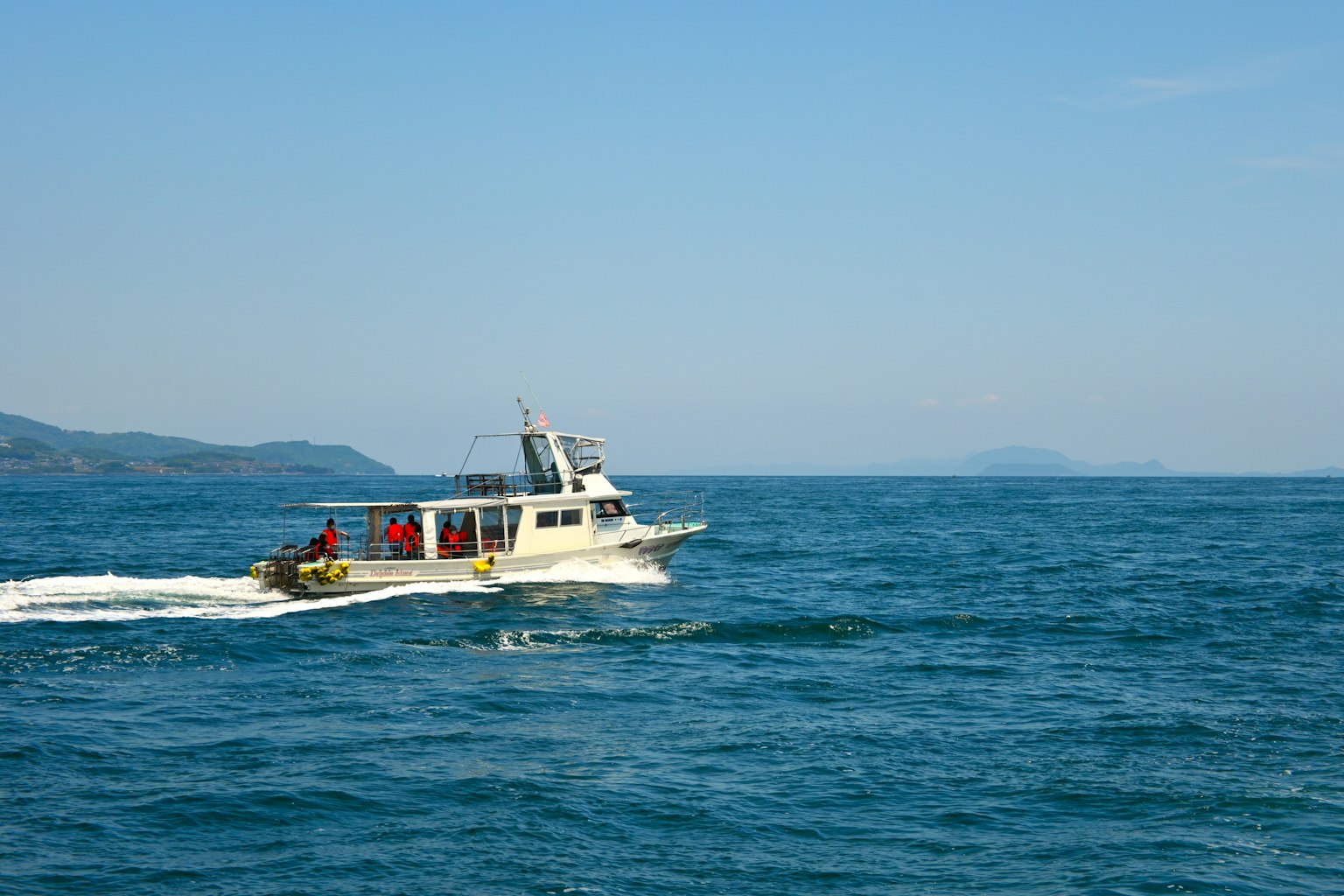 Petit bateau naviguant dans la mer bleue avec des montagnes au loin