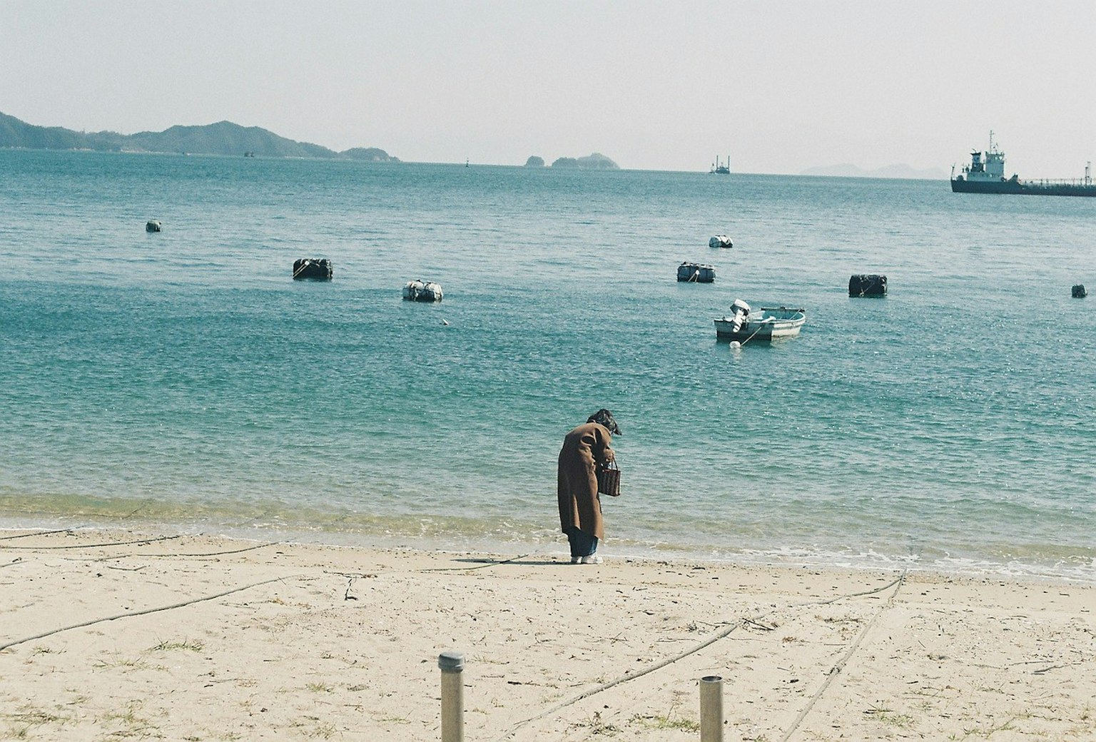 Person walking along the beach with calm water in the background