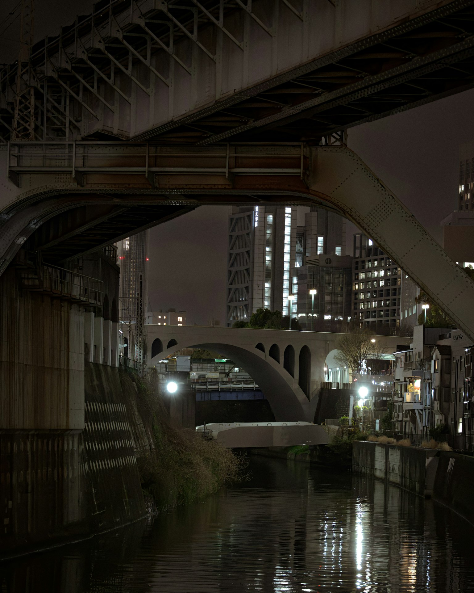 ฉากเมืองยามค่ำคืนที่มีสะพานและการสะท้อนในน้ำ