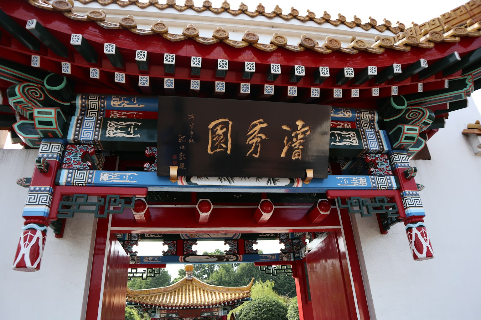 傳統中國門，裝飾有紅色和黑色的裝飾，中央有金色字符的標誌