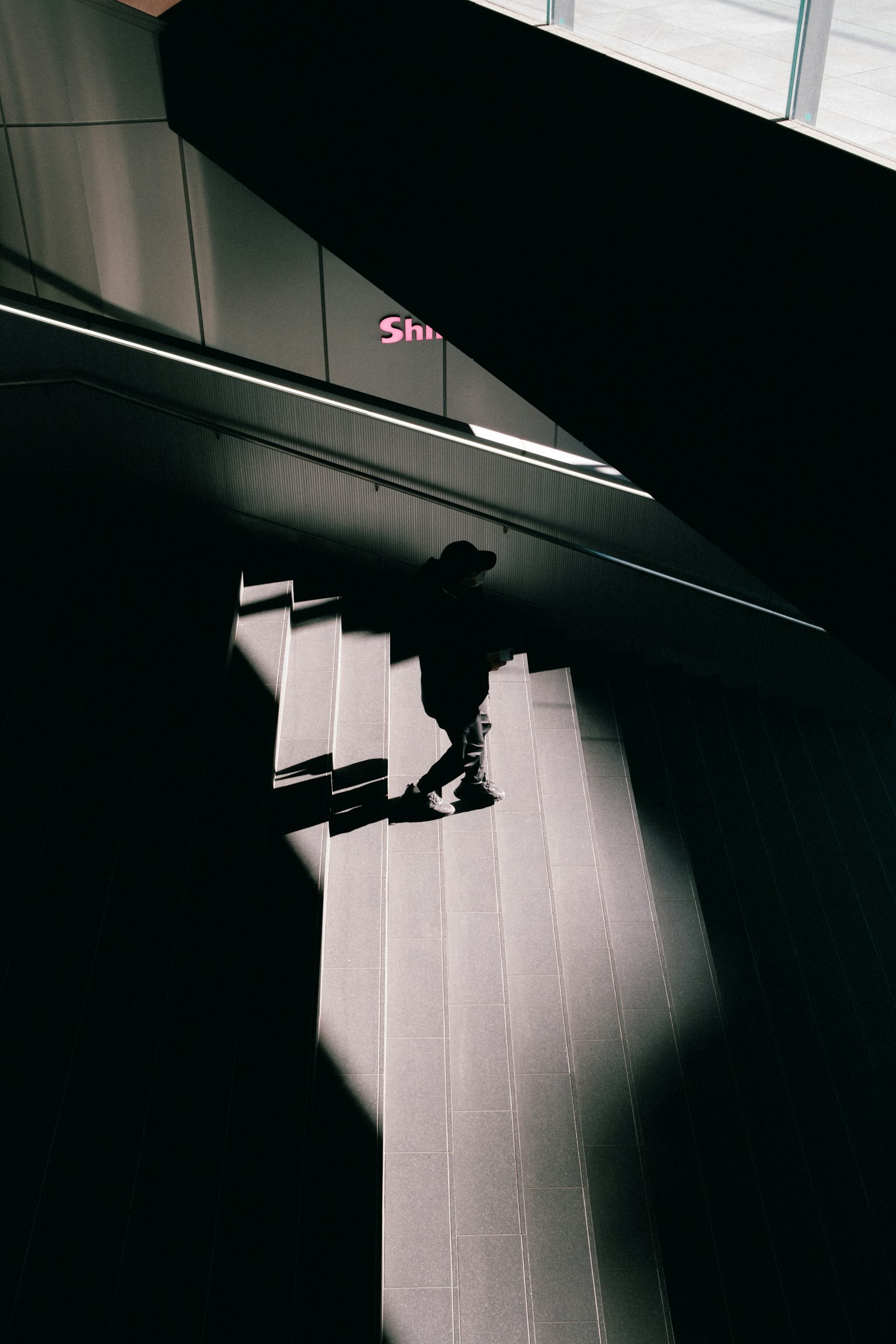 Shadow of a person descending stairs in a modern building interior